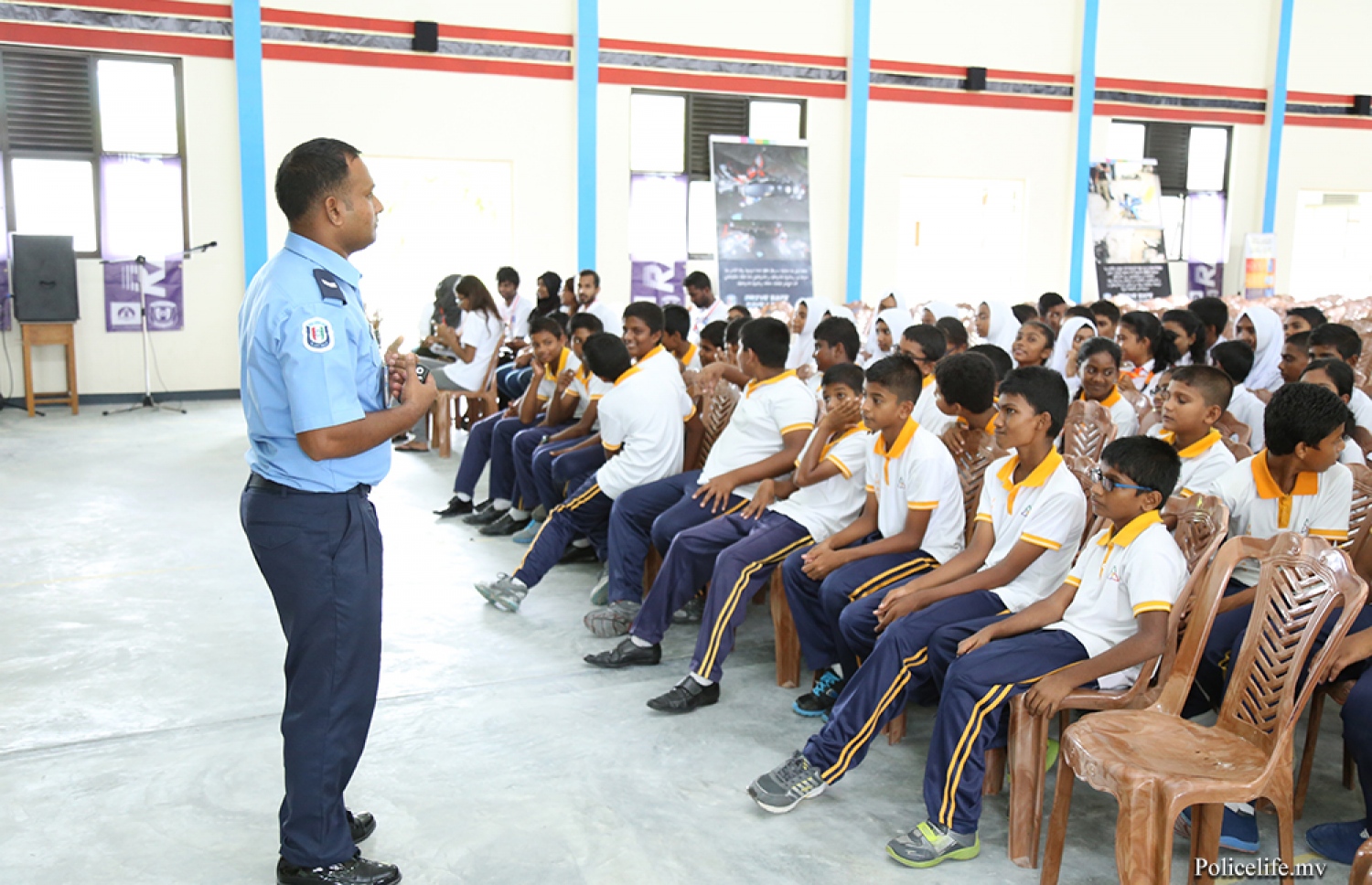 ލ. އަތޮޅު: މޭ 9، 2016: ފުލުހުންނާ އެލައިޑް އިންސިއުރެންސާ އެކުވެގެން ލ. އަތޮޅުގު ބައެއް ރަށްރަށުގައި ޓްރެފިކާ ގުޅޭގޮތުން އާންމުން ހޭލުންތެރިކުމަށް ބޭއްވި "ރައްކާ" ޕްރޮގްރާމުގައި ފުލުހަކު ދަރިވަރުންނަށް ކިޔަވާދެނީ.-- ފޮޓޯ: ޕޮލިސް