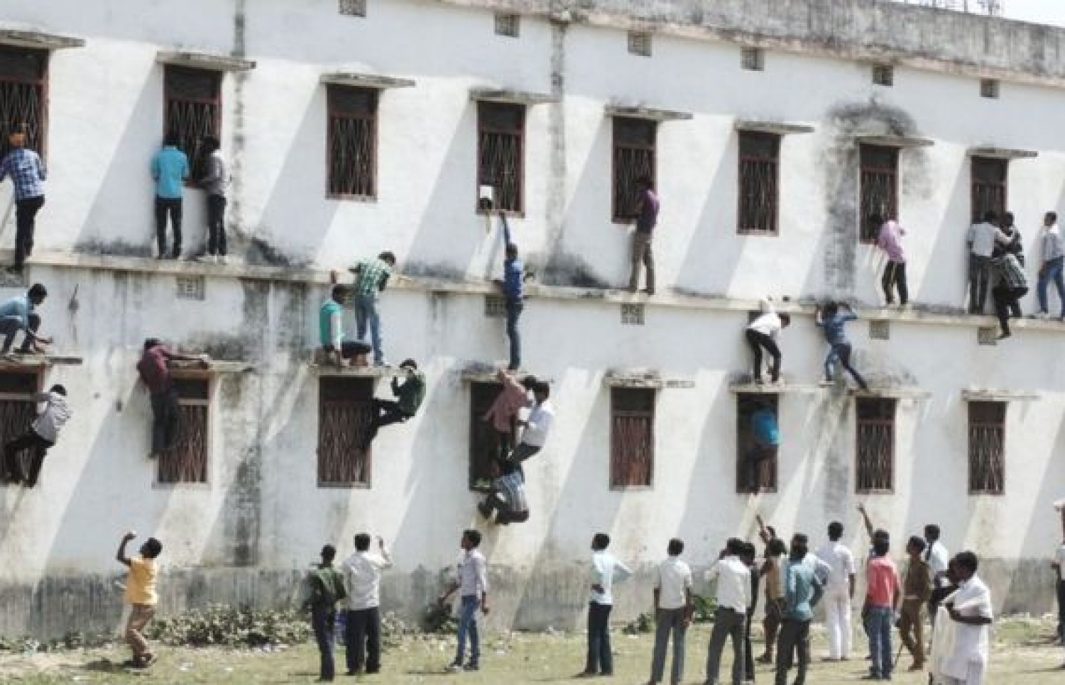 ބިހާރު ސްޓޭޓުގައި މިދިޔަ އަހަރު ބޭއްވި އިމްތިހާނުގައި ދަރިވަރުންނަށް ޖަވާބު ކަރުދާސް ދިނުމަށް ބެލެނިވެރިން ފާރު މައްޗަށް އަރަނީ. --ފޮޓޯ:ބީބީސީ