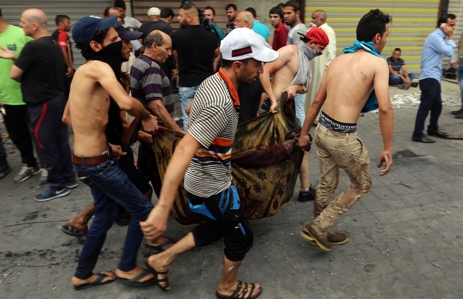 ބަޣުދާދުގައި ބޮމުގެ ހަމަލާ ދިން ތަނުން މަރުވި މީހެއްގެ ހަށިގަނޑު ގެންދަނީ. --ފޮޓޯ:އޭއެފްޕީ