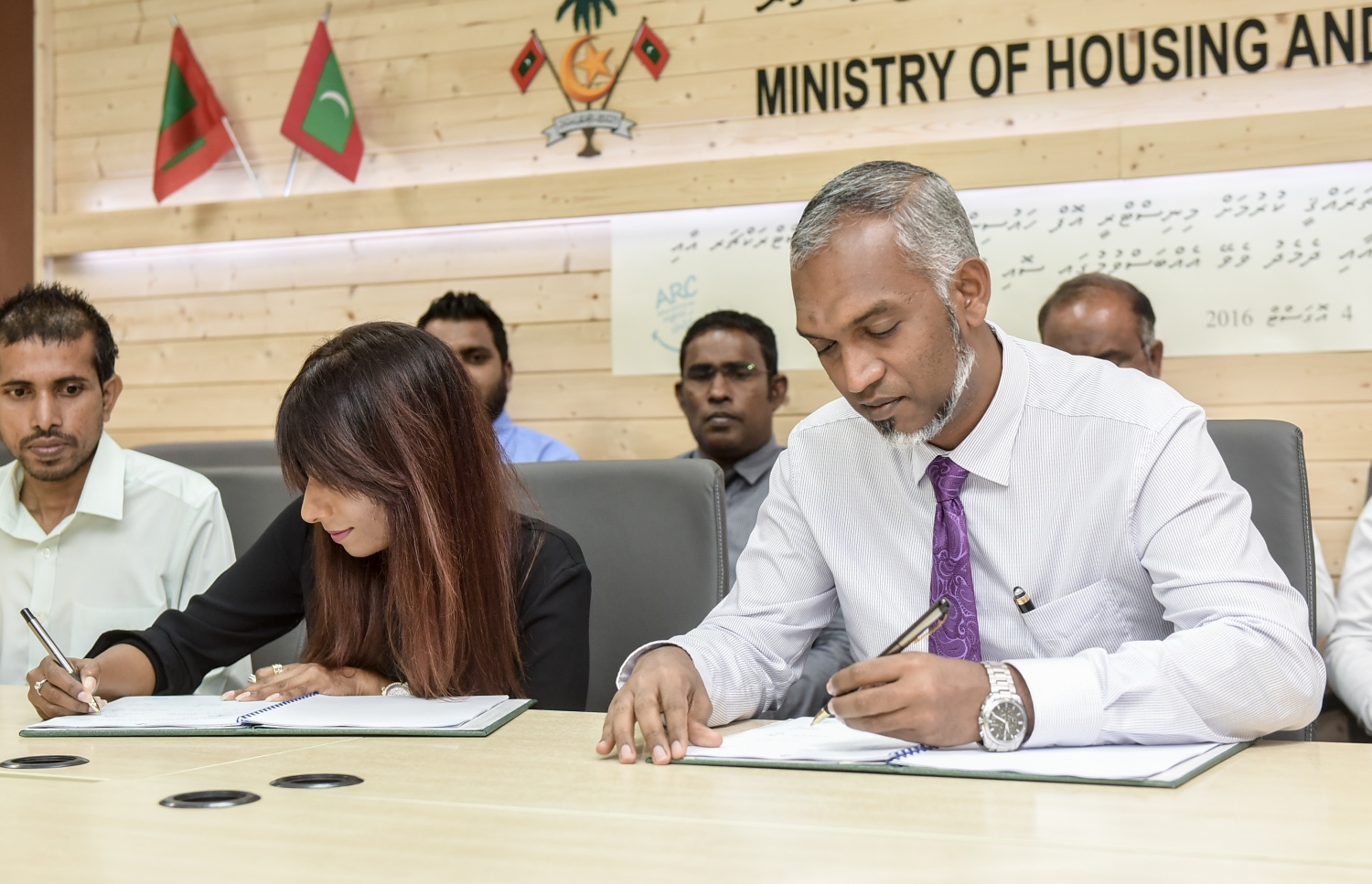 އުސްގެކޮޅު ތަރައްގީކުރަން އާކާ ހަވާލުކުރުމުގެ އެއްބަސްވުމުގައި ހައުސިން މިނިސްޓަރު ޑރ. މުއިއްޒާއި (ކ) އަދި އާކުގެ ވަގުތީ ޑިރެކްޓަރު ޖެނެރަލް ޒީނާ ސޮއިކުރައްވަނީ.-- ފޮޓޯ: ނިޝާން އަލީ/ މިހާރު