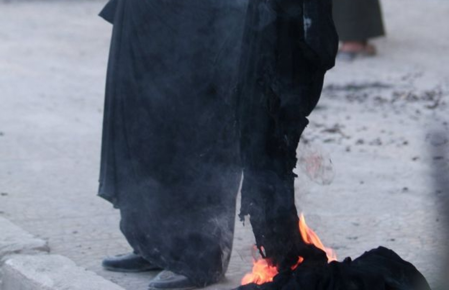 އައިއެސްގެ އަތް ދަށުން މަންބިޖު މިނިވަންވުމާ އެކު އަންހެނެއްގެ މޫނު ބުރުގާ އަންދާލަނީ. ފޮޓޯ:ރޮއިޓާސް