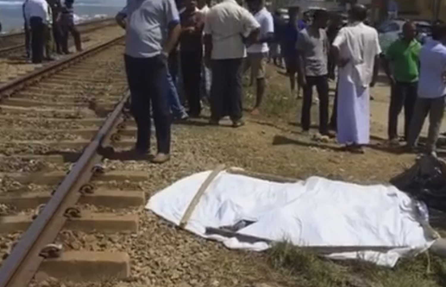 ލަންކާގައި އެކްސިޑެންޓްވި ސަރަހައްދަށް މީހުން އެއްވެފައި އޮތްއިރު، އިޒްހާމް ހަށިގަނޑުގައި ހުދު ފޮތިގަނޑެއް އަޅާފައި.