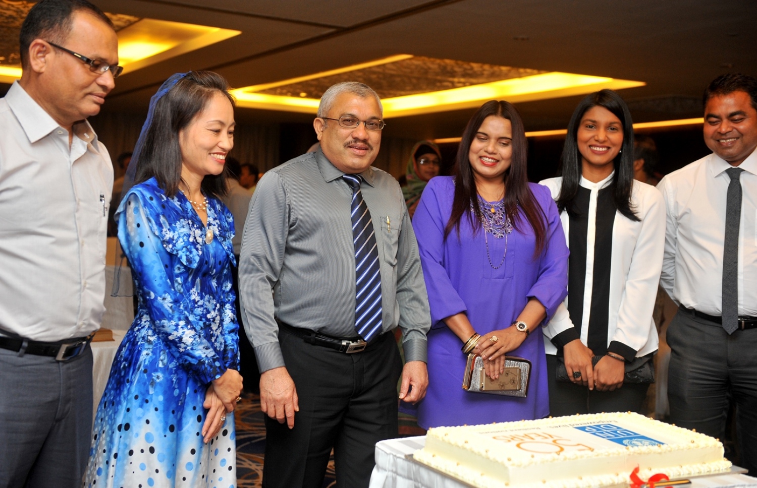 މާލެ: އޮކްޓޯބަރު 5، 2016: ތަރައްގީއާ ބެހޭ އދ.ގެ ޖަމިއްޔާ ޔޫއެންޑީޕީ އަށް 50 އަހަރު ފުރުން ފާހަގަ ކުރުމަށް ހޮޓެލް ޖެންގައި ބޭއްވި ރަސްމިއްޔާތުގައި ޔޫއެންޑީޕީން ރާއްޖެއަށް ކަނޑައަޅުއްވާފާ ހުންނަ މަންދޫބު ނޯޑާއާ(ވ-2)، ނައިބު ރައީސް ޖިހާދު(ވ-3)، ޑިފެންސް މިނިސްޓަރު އާދަމް ޝަރީފް(ވ)، ޔޫތު މިނިސްޓަރު އިރުތިޝާމް(ކ-3)، ޖެންޑާ މިނިސްޓަރު ޒެނީޝާ(ކ-2) އަދި އެންވަޔަރްމެންޓް މިނިސްޓަރު ތޯރިގް(ކ) ކޭކް ފެޅުމުގައި ބައިވެރިވެ ވަޑައިގަންނަވަނީ.-- ފޮޓޯ: ރައީސް އޮފީސް