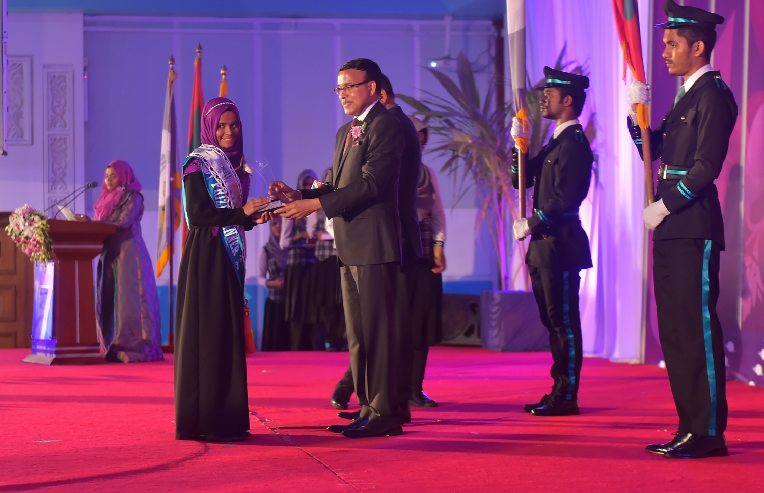 މާލެ: އޮކްޓޯބަރު 8، 2016- އަހުމަދިއްޔާ އިންޓަނޭޝަނަލް ސްކޫލުގެ އިނާމު ދިނުމަށް ބޭއްވި ޖަލްސާގެ ޝަރަފުވެރި މެހުމާން އެޑިއުކޭޝަން މިނިސްޓްރީގެ ސްޓޭޓް މިނިސްޓަރު ޑރ. އަބްދުﷲ ނަޒީރު އިނާމު ހަވާލުކޮށްދެއްވަނީ: އެ ސްކޫލުން މިދިޔަ އަހަރު ސެކަންޑަރީ ބައިން އެއްވަނަ ހޯދީ ފާތިމަތު ނަޝާ އަލީ އަދި ހަޔަ ސެކަންޑްރީ ބައިގެ އެއްވަނަ ދަރިވަރަކީ އާމިނަތު ރިފްޒާ.---ފޮޓޯ: މުހައްމަދު ޝަރުހާން/މިހާރު