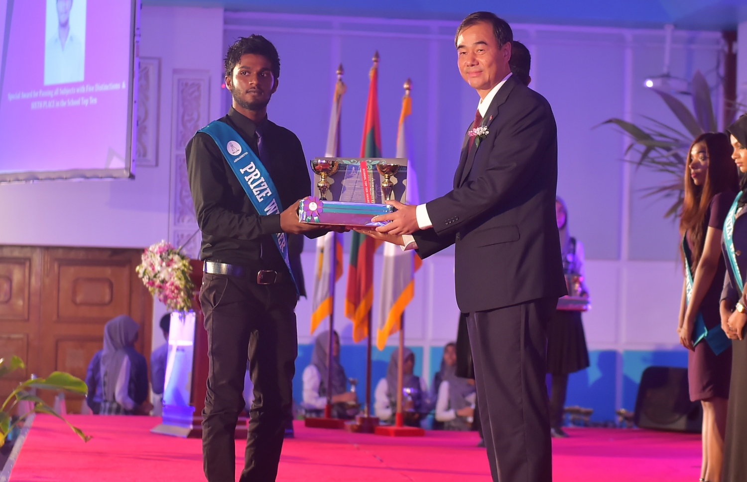 މާލެ: އޮކްޓޯބަރު 8، 2016- އަހުމަދިއްޔާ އިންޓަނޭޝަނަލް ސްކޫލުގެ އިނާމު ދިނުމަށް ބޭއްވި ޖަލްސާގައި، ރާއްޖޭގައި ހުންނަވާ ޗައިނާގެ ސަފީރު، ދަރިވަރަކާ އިނާމު ހަވާލުކޮށްދެއްވަނީ: އެ ސްކޫލުން މިދިޔަ އަހަރު ސެކަންޑަރީ ބައިން އެއްވަނަ ހޯދީ ފާތިމަތު ނަޝާ އަލީ އަދި ހަޔަ ސެކަންޑްރީ ބައިގެ އެއްވަނަ ދަރިވަރަކީ އާމިނަތު ރިފްޒާ.---ފޮޓޯ: މުހައްމަދު ޝަރުހާން/މިހާރު