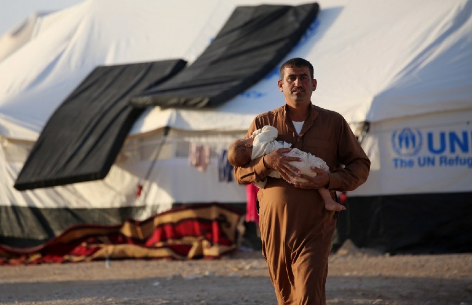 މޫސަލްގެ ހަމަލާތަކުން ސަލާމަތްވުމަށް ދިޔަ މީހަކު ރެފިއުޖީ ކޭމްޕެއްގައި ކުޑަ ކުއްޖަކު ގޮވައިގެން. --ފޮޓޯ:އޭއެފްޕީ