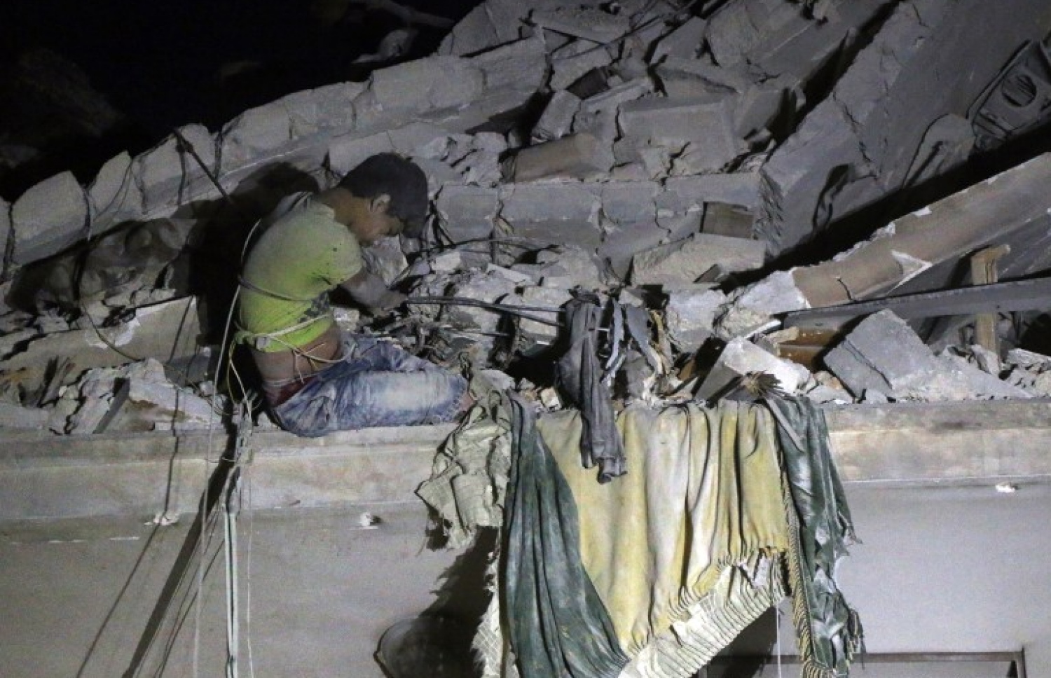 ސީރިއާގެ ހަލަބަށް އިއްޔެ ދިން ވައިގެ ހަމަލާތަކުގައި ވެއްޓިފައިވާ އިމާރާތެއްގެ ކައިރީގައި ކުޑަ ކުއްޖަކު ސަލާމަތް ކުރަންދެން މަޑުކޮށްލައިގެން. --ފޮޓޯ:އޭއެފްޕީ