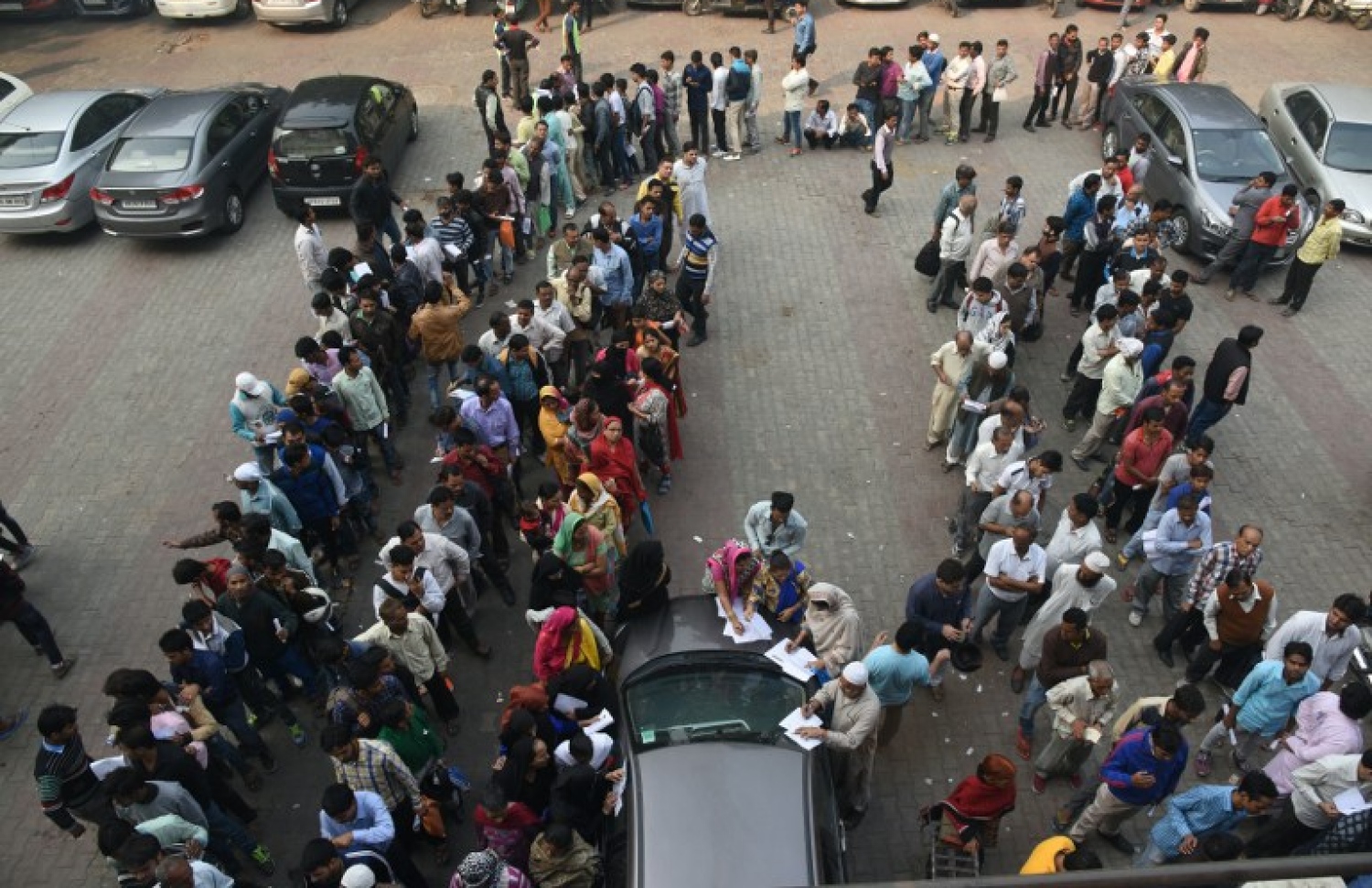 ފައިސާ ޖަމާކުރާށާއި ކުރީގެ ނޫޓު ބަދަލު ކުރުމަށް ނިއު ދިއްލީގެ ބޭންކެއްގެ ކައިރީ މީހުން ކިޔޫ ހަދާފައި. --ފޮޓޯ:އޭއެފްޕީ