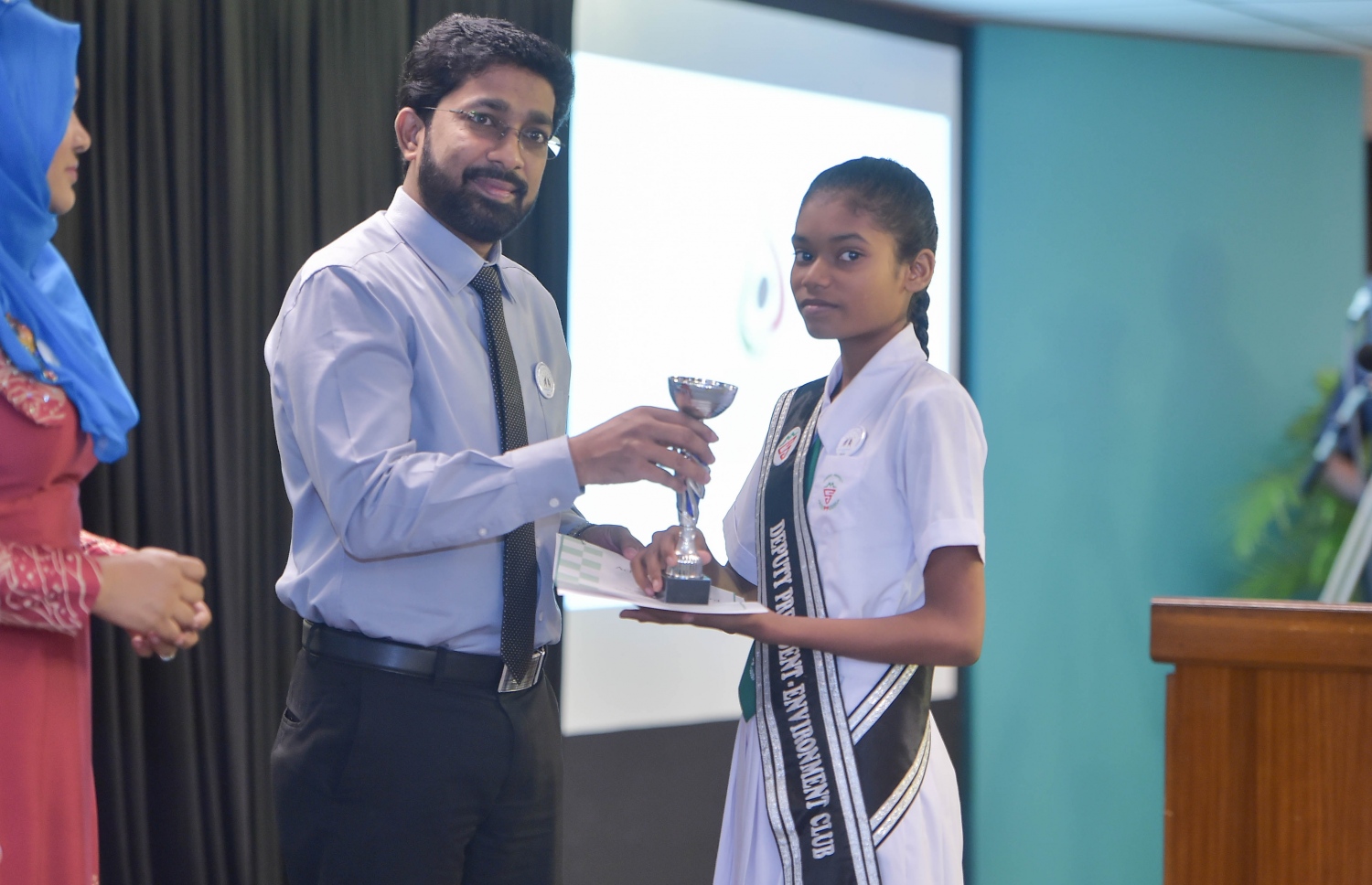 އެޗްއާރުސީއެމުން ސްކޫލުތަކަށް ހުޅުވާލައިގެން ބޭއްވި މުބާރާތުން ވަނައެއް ހޯދި ކުއްޖަކަށް ހޯމް މިނިސްޓަރު އަޒްލީން ތަށި ހަވާލުކޮށްދެއްވަނީ.---ފޮޓޯ: މުހައްމަދު ޝަރުހާން/މިހާރު