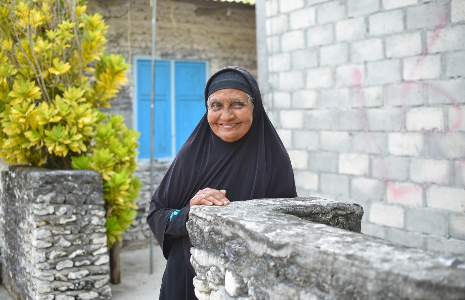 ހއ. މޮޅަދޫގައި ގެއެއްގެ ދޮރުމަތީގައި، އުމުރުން ދުވަސްވީ އަންހެނަކު މަޑުކޮށްލައިގެން. -- ފޮޓޯ: އަބްދުﷲ އައުރާފް/މިހާރު