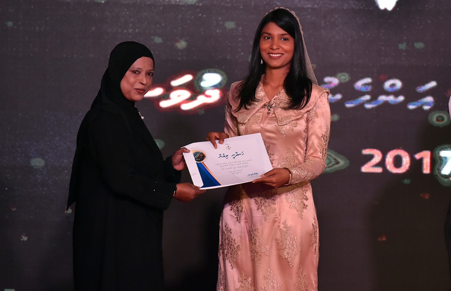 މާލެ: މާޗް 8، 2017: ބައިނަލްއަގުވާމީ އަންހެނުންގެ ދުވަސް ފާހަގަކުރަން ދަރުބާރުގޭގައި ބޭއްވި ޖަލްސާއެއްގައި ރެހެނދި އެވޯޑް ލިބުނު ކަނބަލަކަށް ޖެންޑާ މިނިސްޓަރު ޒެނީޝާ (ކ)، ހަނދާނީ ލިޔުން ހަވާލުކޮށްދެއްވަނީ.-- ފޮޓޯ: ރައީސް އޮފީސް