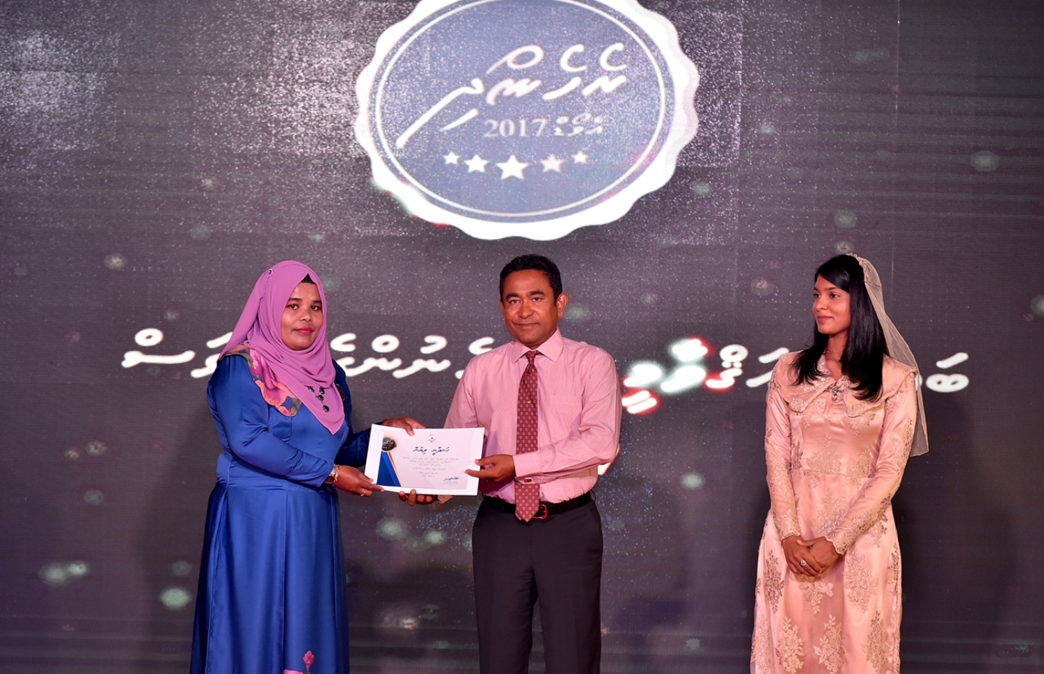 މާލެ: މާޗް 8، 2017: ބައިނަލްއަގުވާމީ އަންހެނުންގެ ދުވަސް ފާހަގަކުރަން ދަރުބާރުގޭގައި ބޭއްވި ޖަލްސާއެއްގައި ރެހެނދި އެވޯޑް ލިބުނު ކަނބަލަކަށް ރައީސް ޔާމީން، ހަނދާނީ ލިޔުން ހަވާލުކޮށްދެއްވަނީ.-- ފޮޓޯ: ރައީސް އޮފީސް