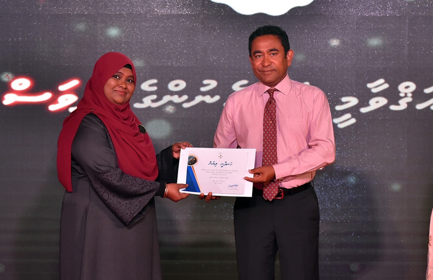 މާލެ: މާޗް 8، 2017: ބައިނަލްއަގުވާމީ އަންހެނުންގެ ދުވަސް ފާހަގަކުރަން ދަރުބާރުގޭގައި ބޭއްވި ޖަލްސާއެއްގައި ރެހެނދި އެވޯޑް ލިބުނު ކަނބަލަކަށް ރައީސް ޔާމީން، ހަނދާނީ ލިޔުން ހަވާލުކޮށްދެއްވަނީ.-- ފޮޓޯ: ރައީސް އޮފީސް