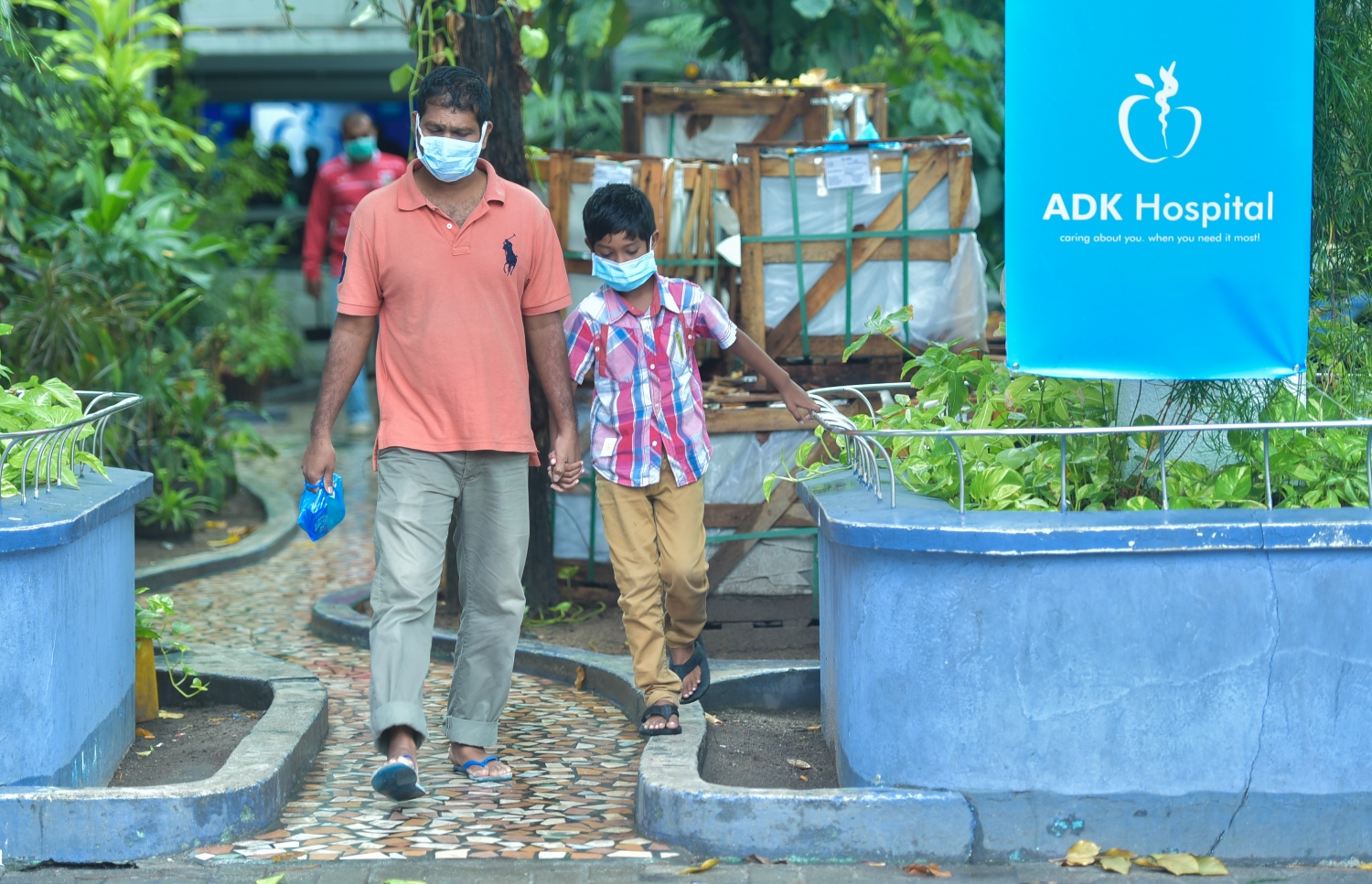 މާލެ: މާޗް 15، 2017- ރާއްޖޭގައި ފެތުރެމުންދާ ސްވައިން ފްލޫއިން ރައްކާތެރި ވުމަށްޓަކައި މޫނުމަތީ މާސްކު އަޅައިގެންހުރި ކުޑަކުއްޖެއް ގޮވައިގެން ހުރި މީހަކު އޭޑީކޭ ހޮސްޕިޓަލުން ނުކުންނަނީ.---ފޮޓޯ: ހުސައިން ވަހީދު/މިހާރު