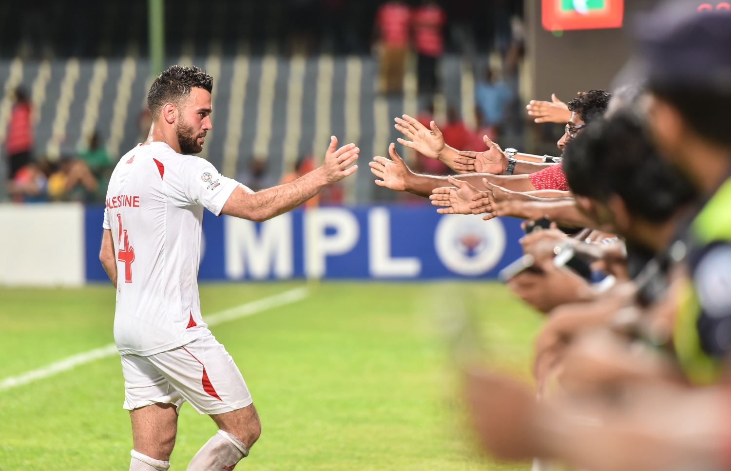 މާލޭގައި ކުޅުނު މެޗުގެ ތެރެއިން ފަލަސްތީން ކުޅުންތެރިއަކު ދިވެހި ސަޕޯޓަރުންނާ ސަލާމްކުރަނީ.-- ފޮޓޯ: ނިޝާން އަލީ/ މިހާރު