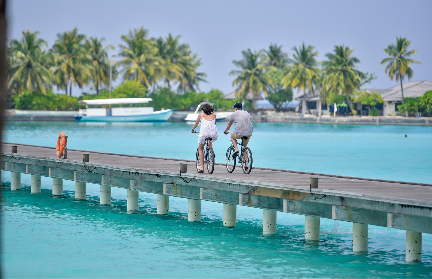 ސަން އައިލެންޑް ރިސޯޓް، މާޗް 5، 2017: ރިސޯޓުގެ މޫދު ކޮޓަރިތައް ގުޅުވާލައިފައިވާ ފާލަމުން ދެ ޓޫރިސްޓަކު ބައިސްކަލްގައި ދަނީ. މި ރިސޯޓުގައި ހުރިހާ ޓޫރިސްޓުން އުޅެނީ ބައިސްކަލްގައި. ސަބަބަކީ ރަށް ބޮޑުވެފައި މުޅި ރަށުގައި ހިނގާފައި އުޅުމަކީ ފަސޭހަ ކަމަކަށް ނުވާތީ. ބައިސްކަލްގައި އުޅުމަކީ ޓޫރިސްޓުންނަށް ވަރަށް ތަފާތު ތަޖުރިބާއެއް -- ފޮޓޯ: ނިޝާން އަލީ/ މިހާރު