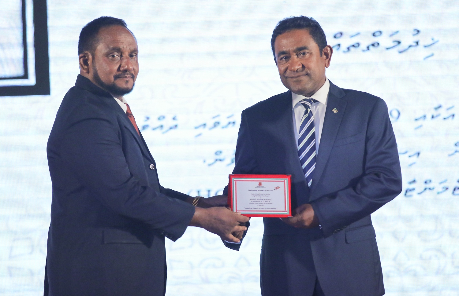 މާލެ: އޭޕްރީލް 20، 2017- މަޖީދިއްޔާ ސްކޫލަށް 90 އަހަރު ފުރުން ފާހަގަކުރުމުގެ ގޮތުން ދަރުބާރުގޭގައި ބޭއްވި ޚާއްސަ ޖަލްސާގައި، އެ ސްކޫލަށް ގިނަ ދުވަސްތަކެއް ވަންދެން ޚިދުމަތް ކުރި މުވައްޒަފަކާ، ރައީސް ޔާމީން ހަނދާނީ ފިލައެއް ހަވާލުކޮށްދެއްވަނީ.---މިހާރު ފޮޓޯ: ހުސެއިން ވަހީދު