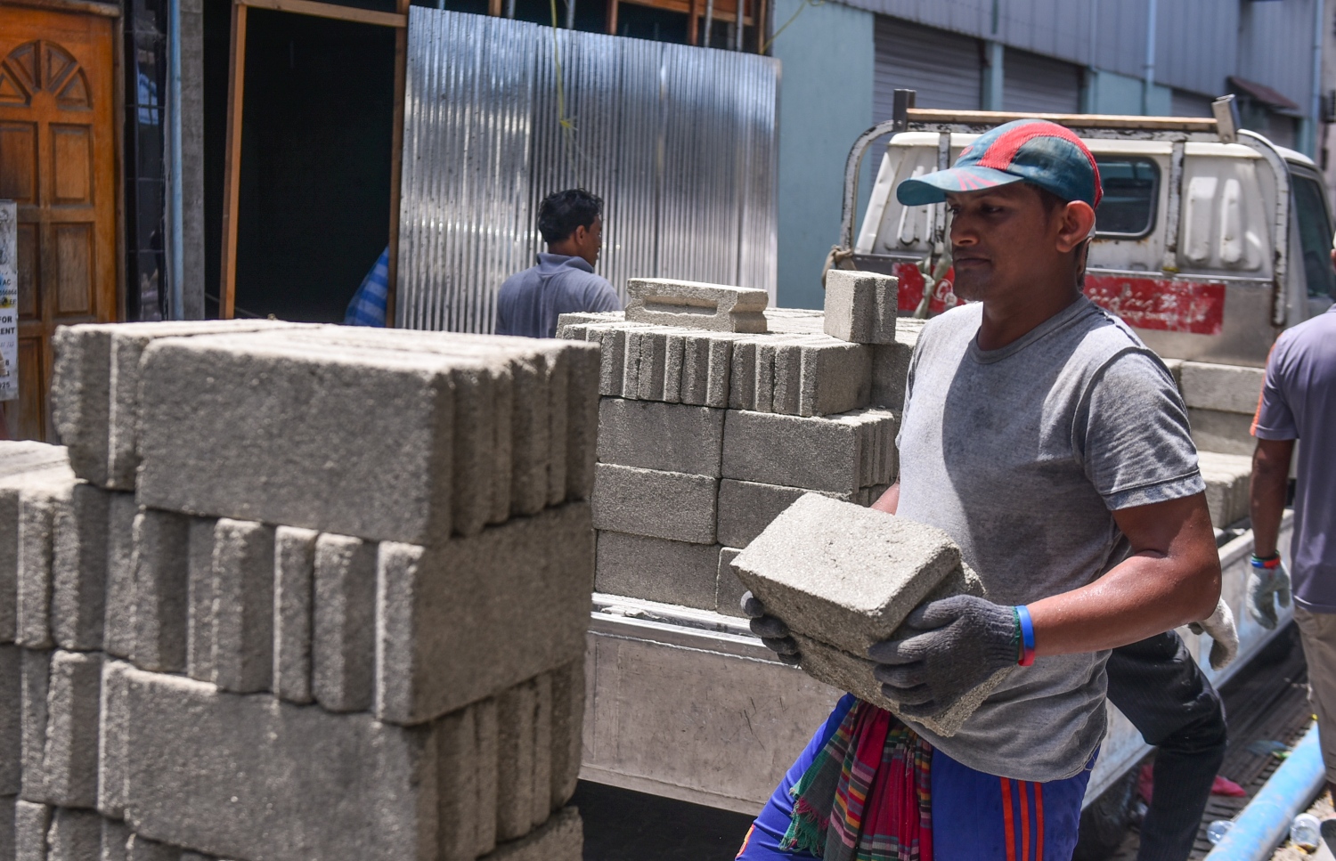 ބިދޭސީއަކު ސިމެންތި ގާތަކެއް އަތުން ހިފައިގެން ކޮންސްޓްރަކްޝަން ސައިޓަކަށް ވަންނަނީ. - ފޮޓޯ: މިހާރު