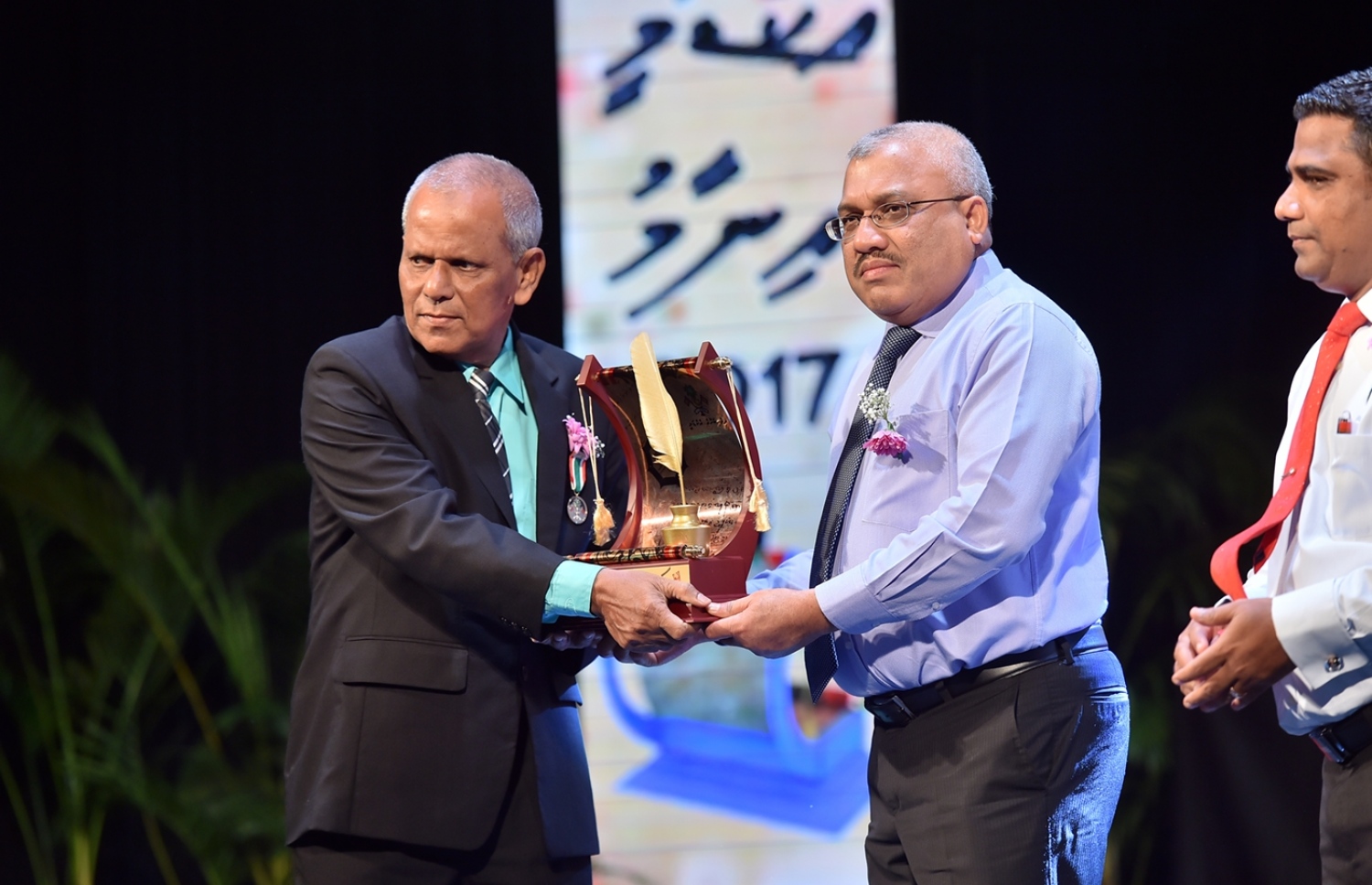 މާލެ: މޭ 16، 2017: ދިވެހި ތާރީޚުގެ ދާއިރާ އިން ދިވެހި ތާރީޚީ ފޮތް އެކުލަވާލައި ލިޔުމުގެ ރޮނގުން މއ. ކަށިމާ، އަހުމަދު ޝާކިރަށް، ނައިބު ރައީސް ޖިހާދު އެވޯޑް ދެއްވަނީ: މިއީ ދިވެހި ބަސް ކުރިއެރުވުމަށް މަސައްކަތް ކުރަމުން އަންނަ ބޭފުޅުންނަށް ހިތްވަރު ދިނުމުގެ ގޮތުން ދިވެހި ބަހުގެ އެކަޑެމީން އަލަށް ތައާރަފުކުރި އެވޯޑެއް: މި ފަހަރު ހަތަރު ދާއިރާއަކުން ފަސް ބޭފުޅަކަށް އެވޯޑް ލިބިވަޑައިގެންނެވި.---ފޮޓޯ: ރައީސް އޮފީސް