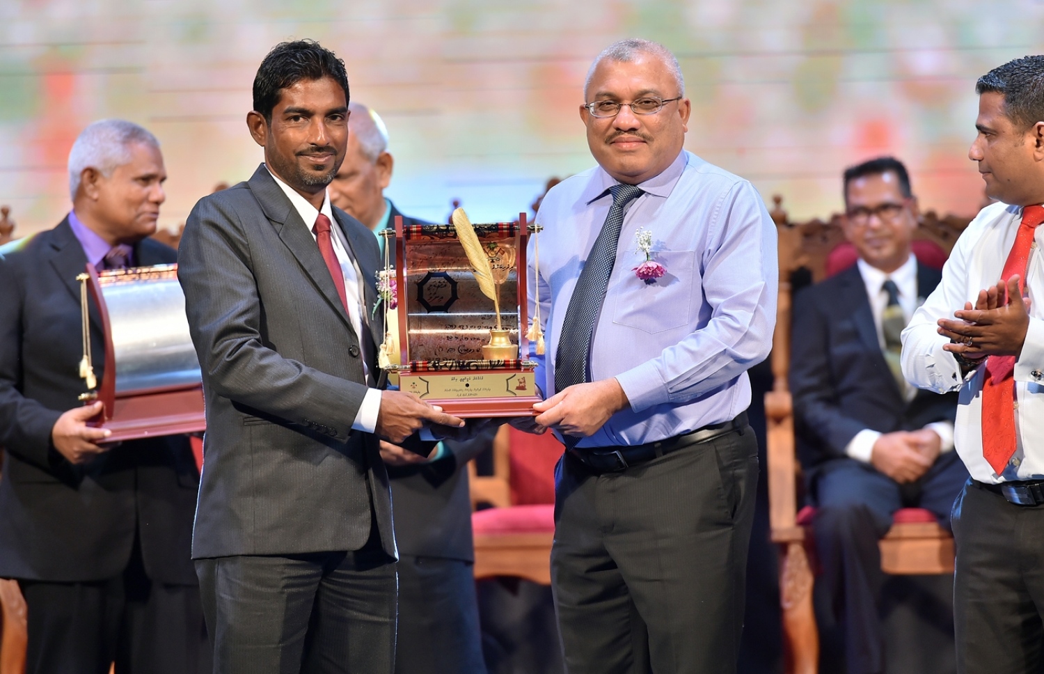 މާލެ: މޭ 16، 2017: ދިވެހި ބަހުގެ ދާއިރާ އިން ދިވެހި ބަސް ކިޔަވައިދިނުމުގެ ރޮނގުން ގ. ކުރޮޅި، އާދަމް ޒާހިރަށް، ނައިބު ރައީސް ޖިހާދު އެވޯޑް ދެއްވަނީ: މިއީ ދިވެހި ބަސް ކުރިއެރުވުމަށް މަސައްކަތް ކުރަމުން އަންނަ ބޭފުޅުންނަށް ހިތްވަރު ދިނުމުގެ ގޮތުން ދިވެހި ބަހުގެ އެކަޑެމީން އަލަށް ތައާރަފުކުރި އެވޯޑެއް: މި ފަހަރު ހަތަރު ދާއިރާއަކުން ފަސް ބޭފުޅަކަށް އެވޯޑް ލިބިވަޑައިގެންނެވި.---ފޮޓޯ: ރައީސް އޮފީސް