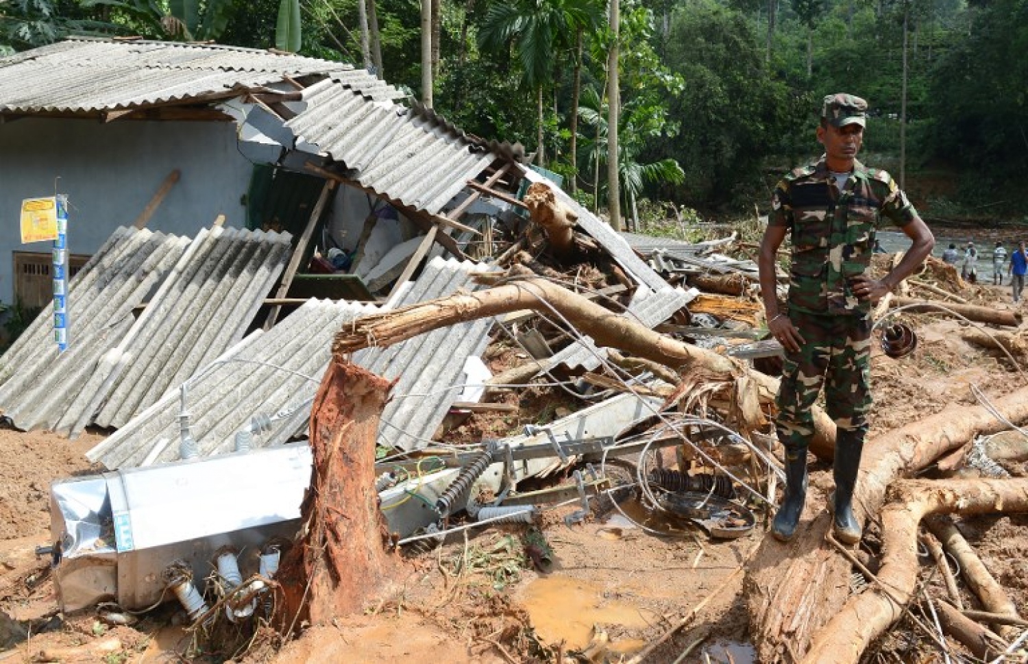 ފެންބޮޑުވުމުގެ ސަބަބުން ކަލުތަރައިން ވެއްޓިފައިވާ ގެއެއްގެ ކައިރީ ސިފައިންގެ މީހަކު ހުއްޓިލައިގެން. --ފޮޓޯ:އޭއެފްޕީ
