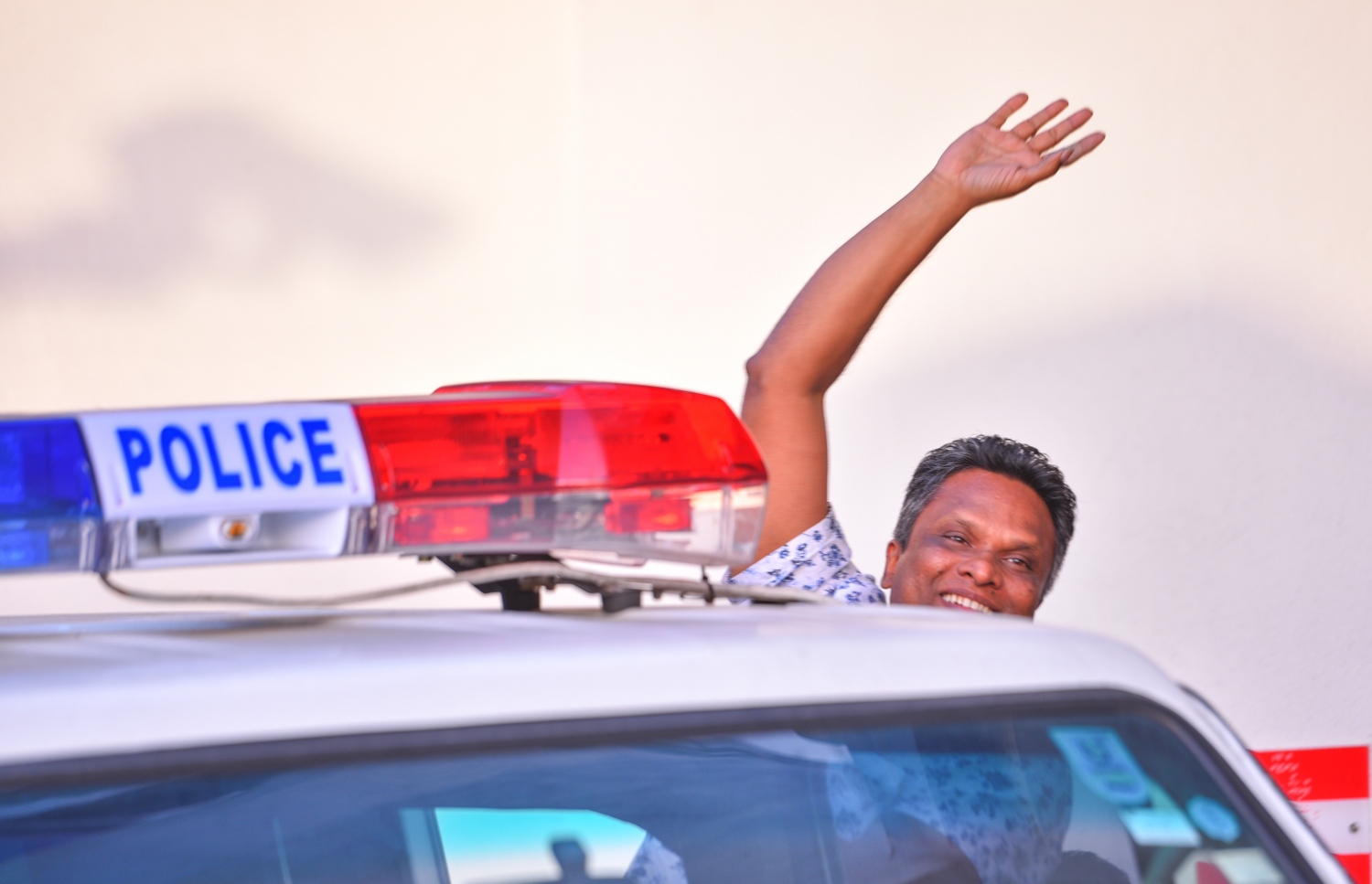 ބަންދުގެ މުއްދަތު ޖެހުމަށް ފަހު އާޒިމް ދޫނިދު އަށް ގެންދިއުމަށްޓަކައި ފުލުހުންގެ ވެހިކަލަށް އަރާވަޑައިގަތުމުގެ ކުރިން އޭނާގެ އާއިލާގެ ބޭފުޅުންނަށް އަތުން އިޝާރާތް ކުރައްވަނީ.---މިހާރު ފޮޓޯ: ހުސެއިން ވަހީދު