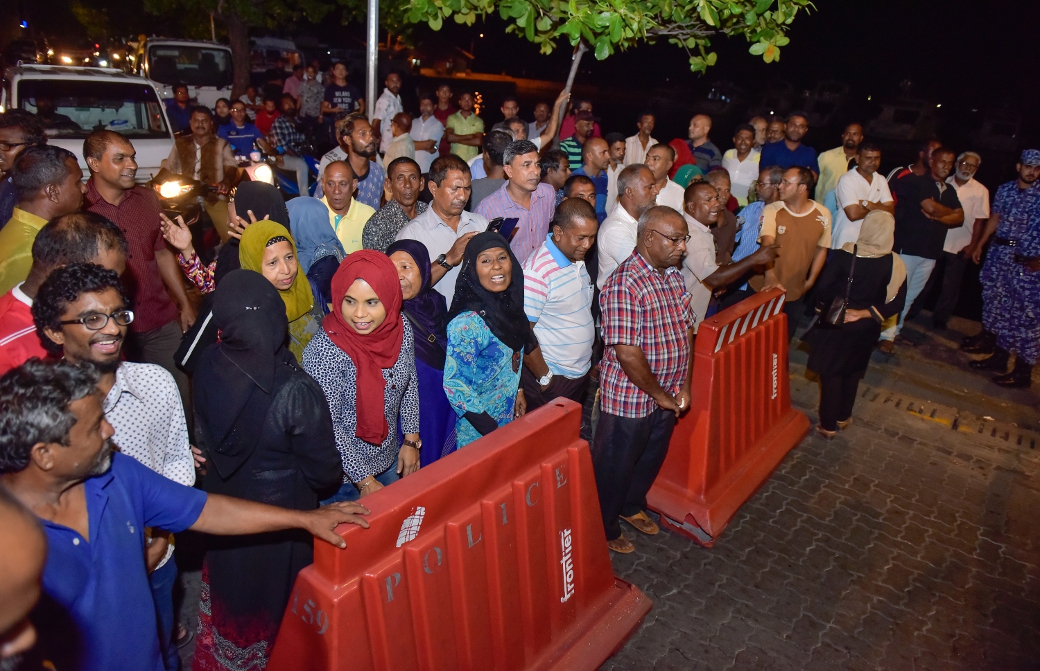 މާލެ: ޖޫން 14، 2017- ކުރީގެ ރައީސް މައުމޫން ތިން މަހެއްހާ ދުވަހު ރާއްޖެ އިން ބޭރުގައި އުޅުއްވުމަށް ފަހު، އެނބުރި ވަޑައިގަންނަވާތީ އެމަނިކުފާނަށް މަރުހަބާ ދެންނެވުމަށް އެއްވި ބައެއް މީހުން ބެރިކޭޑުގެ ފަހަތަށް ޖައްސާފައި.---މިހާރު ފޮޓޯ: ނިޝާން އަލީ