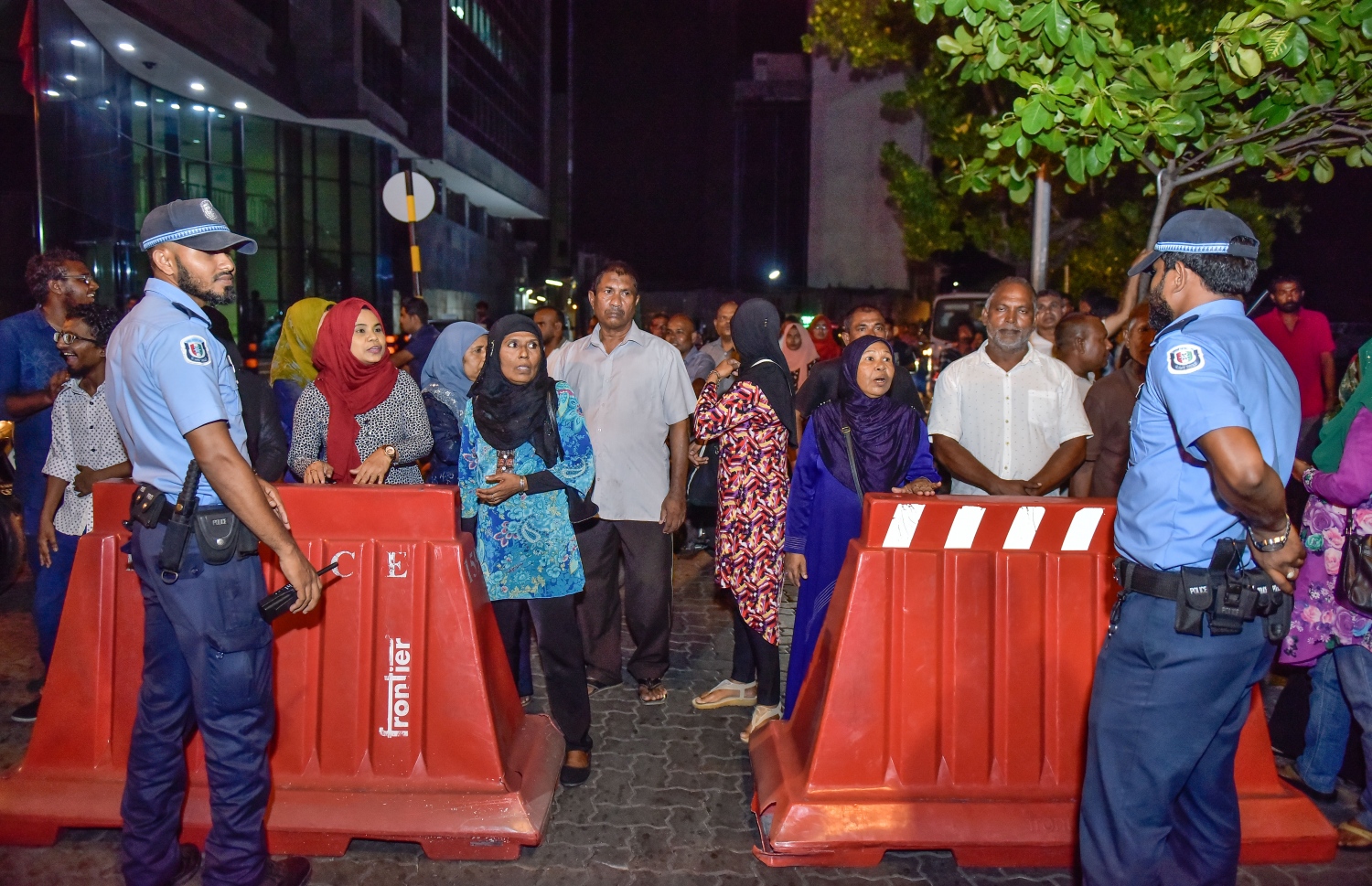 މާލެ: ޖޫން 14، 2017- ކުރީގެ ރައީސް މައުމޫން ތިން މަހެއްހާ ދުވަހު ރާއްޖެ އިން ބޭރުގައި އުޅުއްވުމަށް ފަހު، އެނބުރި ވަޑައިގަންނަވާތީ އެމަނިކުފާނަށް މަރުހަބާ ދެންނެވުމަށް އެއްވި ބައެއް މީހުން ބެރިކޭޑުގެ ފަހަތަށް ޖައްސާފައި.---މިހާރު ފޮޓޯ: ނިޝާން އަލީ