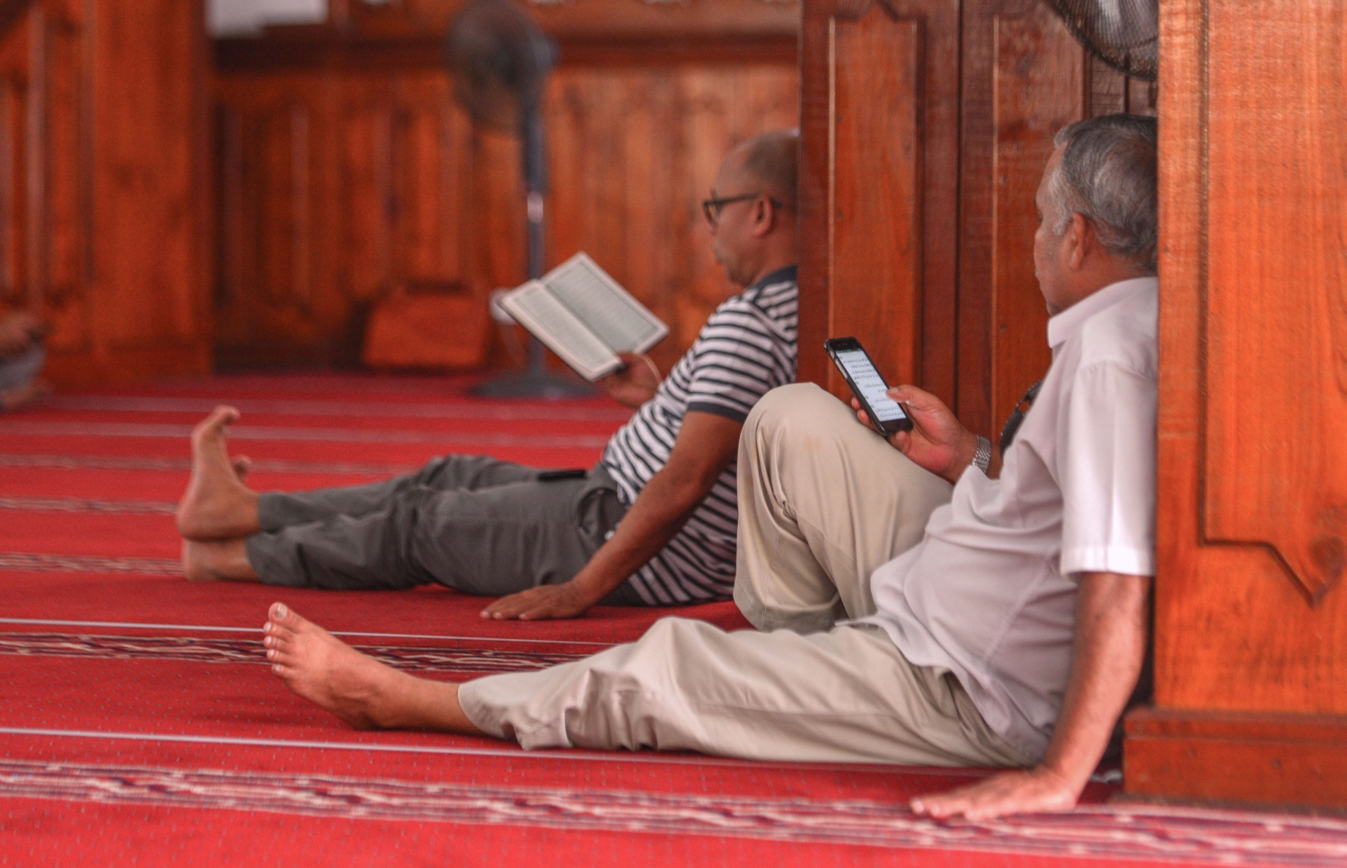 މާލެ: ޖޫން 17، 2017- މިސްކިތެއްގައި މީހަކު މޮބައިލް ފޯނުން ޤުރުއާން ކިޔަވާއިރު، ދުރުގައި އެހެން މީހަކު މުސްހަފުން ކިޔަވަނީ. ޒަމާނަށް އައި ބަދަލާއެކު މޮބައިލް ފޯޏނުން ޤުރުއާން ކިޔަވާ މީހުން ގިނަ.---މިހާރު ފޮޓޯ: ހުސެއިން ވަހީދު