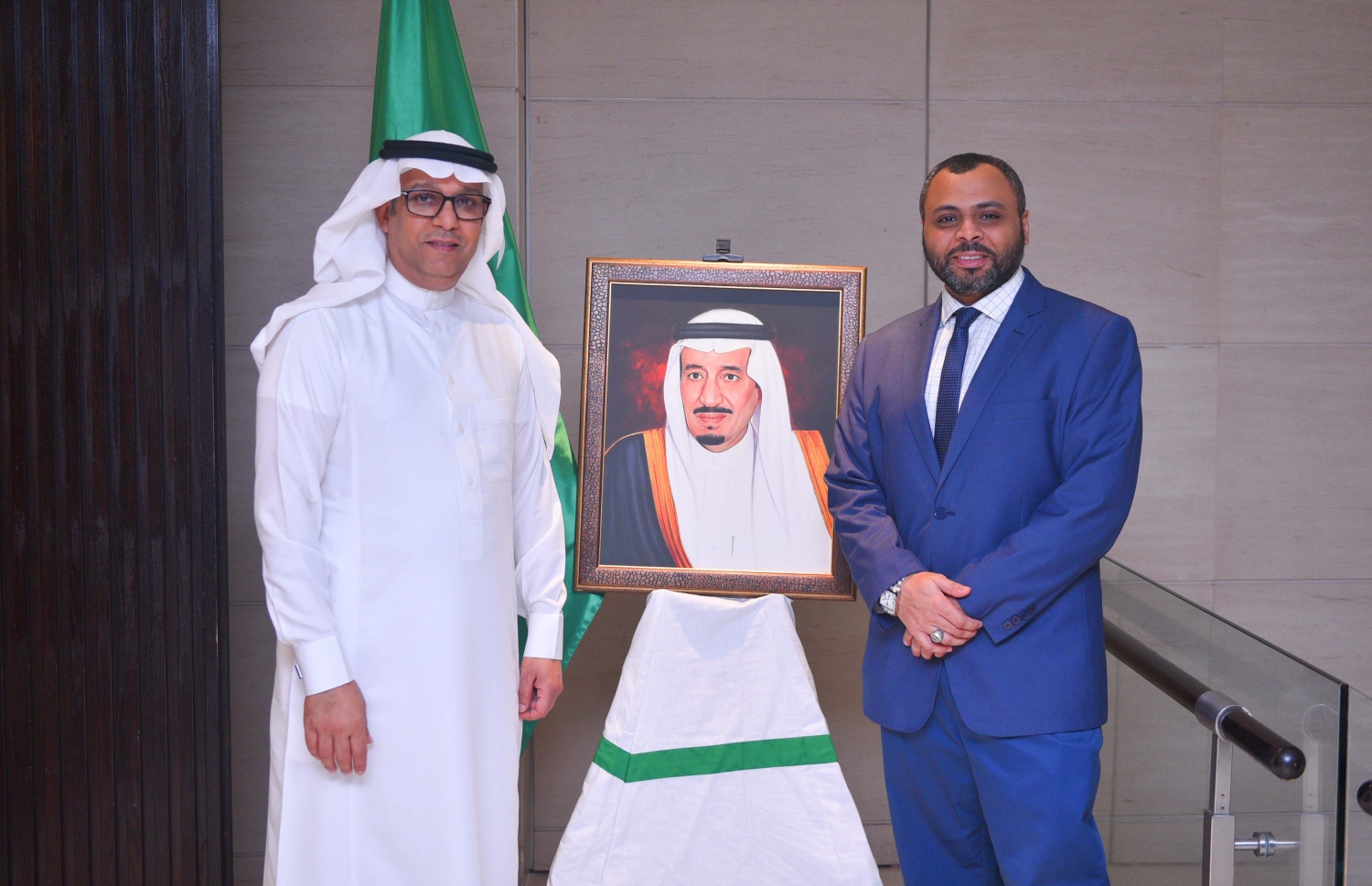 މާލެ: ޖޫން 16، 2017- ރާއްޖޭގައި ހުންނަ ސައޫދީ އެމްބަސީގެ ފަރާތުން ދިވެހި ދައުލަތުގެ އިސްވެރިންނަށް ބޭއްވި ރޯދަވީއްލުމުގެ ހަފުލާގައި ބަހައްޓާފައި ހުރި، އެ ގައުމުގެ ރަސްގެފާނު ސަލްމާންގެ ފޮޓޯފުޅުގެ ކައިރީގައި ސައޫދީ އެމްބަސީގެ އިސް ދެ އޮފިޝަލަކު ފޮޓޯއެއް ނަންގަވަނީ.---މިހާރު ފޮޓޯ: ހުސެއިން ވަހީދު