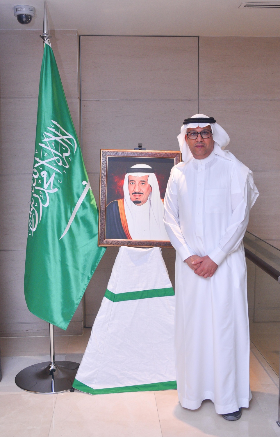 މާލެ: ޖޫން 16، 2017- ރާއްޖޭގައި ހުންނަ ސައޫދީ އެމްބަސީގެ ފަރާތުން ދިވެހި ދައުލަތުގެ އިސްވެރިންނަށް ބޭއްވި ރޯދަވީއްލުމުގެ ހަފުލާގައި ބަހައްޓާފައި ހުރި، އެ ގައުމުގެ ރަސްގެފާނު ސަލްމާންގެ ފޮޓޯފުޅުގެ ކައިރީގައި ސައޫދީ އެމްބަސީގެ އިސް އޮފިޝަލަކު ފޮޓޯއެއް ނަންގަވަނީ.---މިހާރު ފޮޓޯ: ހުސެއިން ވަހީދު