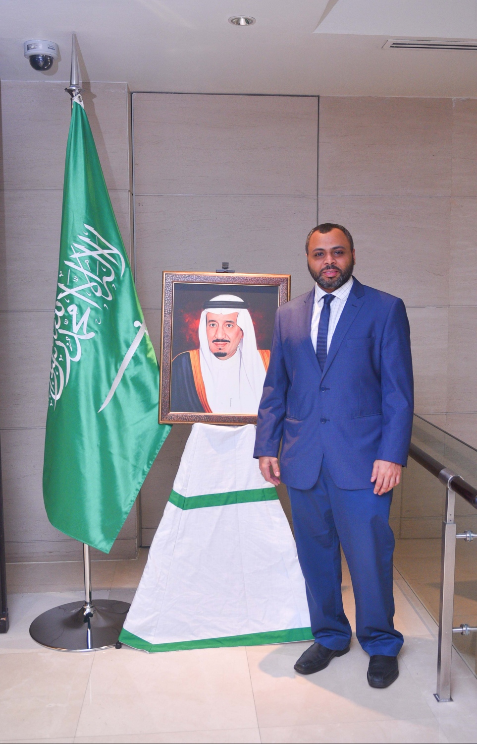 މާލެ: ޖޫން 16، 2017- ރާއްޖޭގައި ހުންނަ ސައޫދީ އެމްބަސީގެ ފަރާތުން ދިވެހި ދައުލަތުގެ އިސްވެރިންނަށް ބޭއްވި ރޯދަވީއްލުމުގެ ހަފުލާގައި ބަހައްޓާފައި ހުރި، އެ ގައުމުގެ ރަސްގެފާނު ސަލްމާންގެ ފޮޓޯފުޅުގެ ކައިރީގައި ސައޫދީ އެމްބަސީގެ އިސް އޮފިޝަލަކު ފޮޓޯއެއް ނަންގަވަނީ.---މިހާރު ފޮޓޯ: ހުސެއިން ވަހީދު