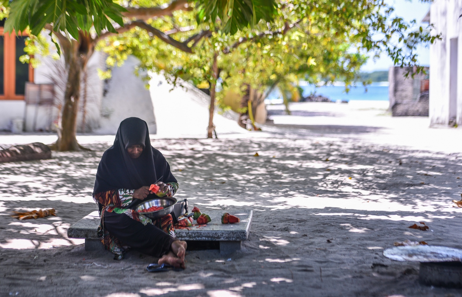 ރ.ކިނޮޅަސް: ޖޫން 28، 2017- ކިނޮޅަހު ގެއެއްގެ ގޯތިތެރޭގައި އަންހެނަކު އިށީނދެގެން އިނދެ ކަށިކެޔޮ ލިޔަނީ.---މިހާރު ފޮޓޯ: ހުސައިން ވަހީދު