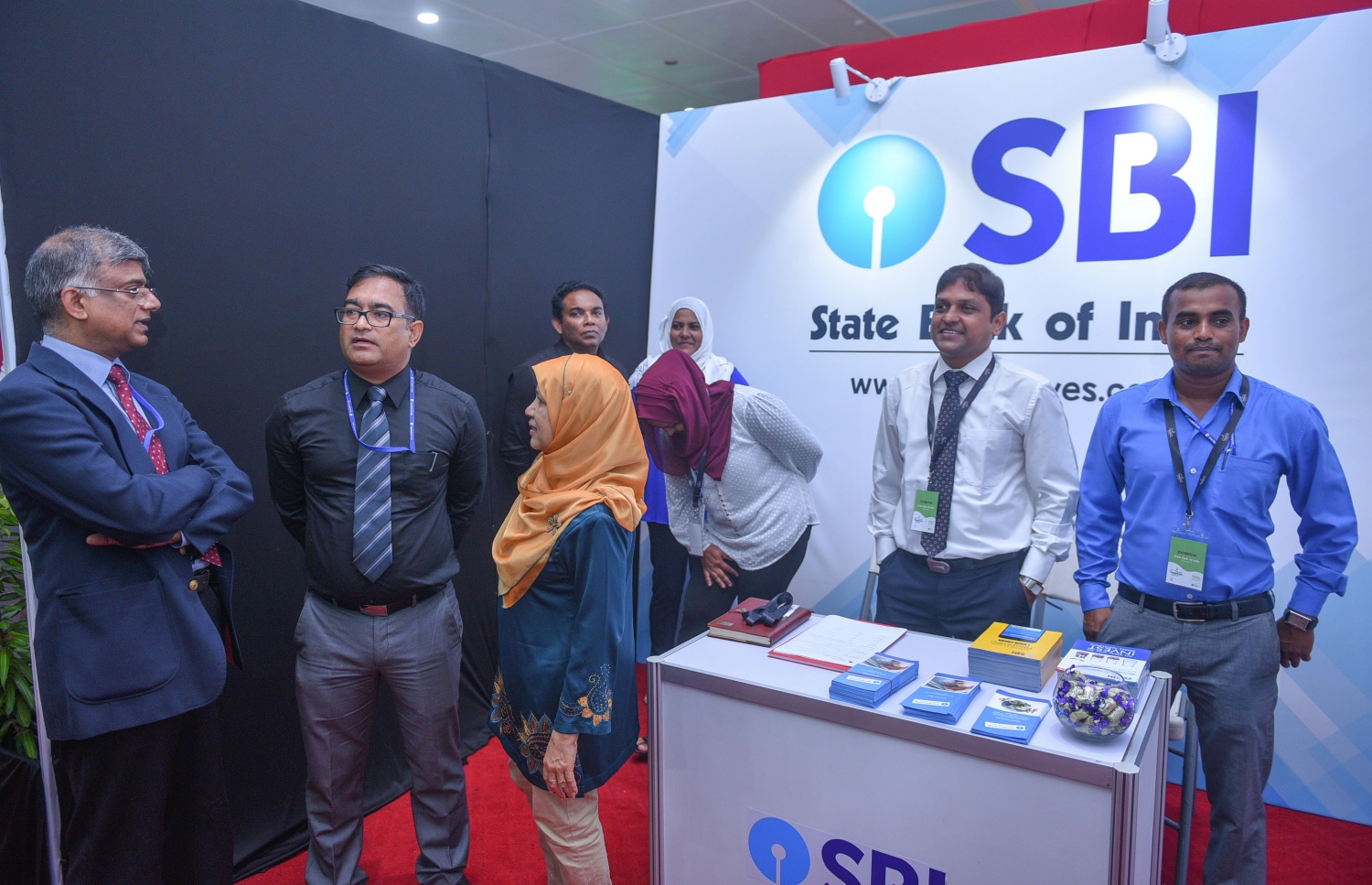 މާލެ: ޖުލައި 6، 2017- ގެދޮރުވެރިކަމަށް ބޭނުންވާ ފައިސާ ހޯދޭނެ ގޮތްތަކާ ބެހޭ ގޮތުން އެމްއެމްއޭ އާއި އެޗްޑީސީ ގުޅިގެން ދަރުބާރުގޭގައި ފެށި މި އަހަރުގެ މޯލްޑިވްސް ފައިނޭންޝަލް އެކްސްޕޯގައި ހުރި ސްޓޭޓް ބޭންކް އޮފް އިންޑިއާ (އެސްބީއައި) ގެ ސްޓޯލެއްގައި އެ ކުންފުނީގެ މުވައްޒަފުންތަކެއް މަޑުކޮށްލައިގެން.---މިހާރު ފޮޓޯ: ހުސެއިން ވަހީދު