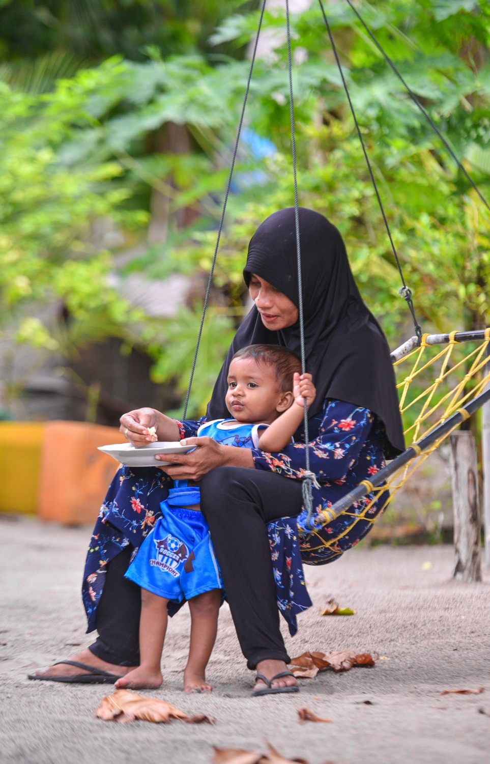 ރ.ފައިނު: ޖުލައި 7، 2017- ޖޯއްޔެއްގައި އިށީނދެލައިގެން އިނދެ، މަންމަޔަކު އޭނާގެ ދަރިފުޅަށް ކާންދެނީ .---މިހާރު ފޮޓޯ: ހުސައިން ވަހީދު