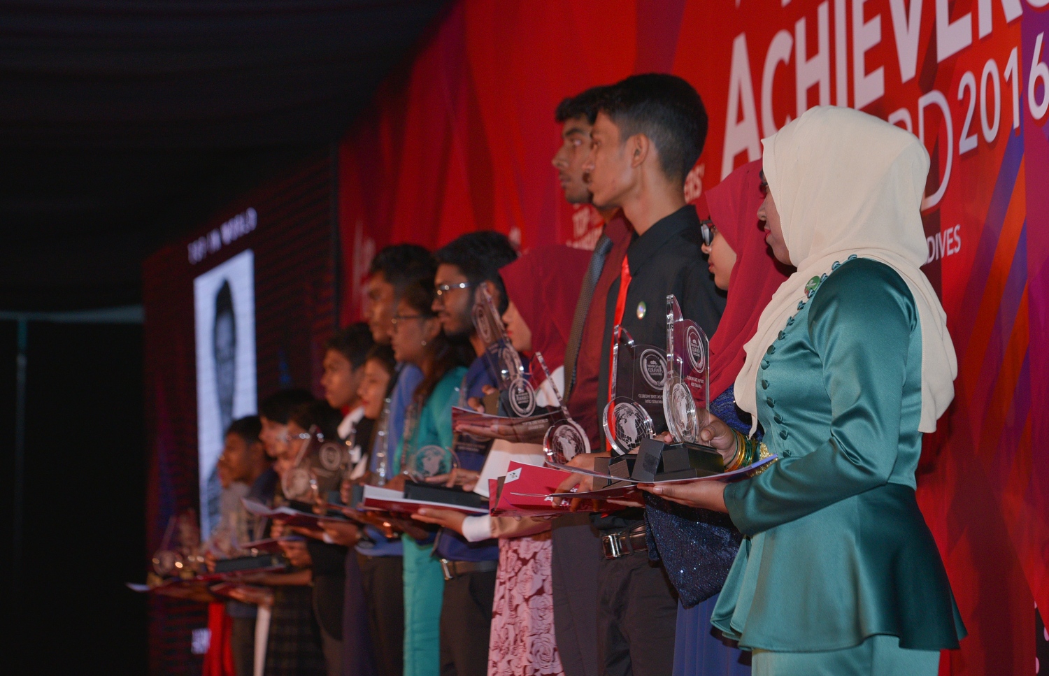 ސާނަވީ އިމްތިހާންގައި ބައިވެރިވެ ވަނަތައް ހޯދި ބައެއް ދަރިވަރުން އިނާމާއި ޓްރޮފީ ހިފައިގެން ސްޓޭޖް މަތީގައި. - ފޮޓޯ: މިހާރު/ ހުސެއިން ވަހީދު