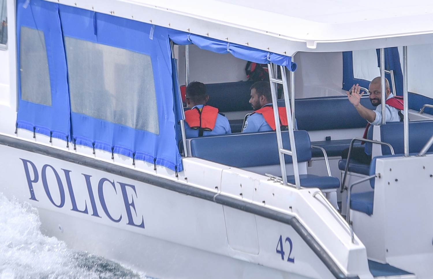 ޖުލައި 18، 2017- ކުރީގެ ރައީސް މައުމޫންގެ ދަރިކަލުން އަދި ދިއްގަރު ދާއިރާގެ މެމްބަރު ފާރިސް މައުމޫން ހައްޔަރުކޮށްގެން، ފުލުހުންގެ ލޯންޗެއްގައި ދޫނިދު އަށް ގެންދާއިރު، އޭނާގެ ސަޕޯޓަރުންނާ އަތުން އިޝާރާތްކޮށް ސަލާމް ކުރައްވަނީ.---މިހާރު ފޮޓޯ: ހުސެއިން ވަހީދު