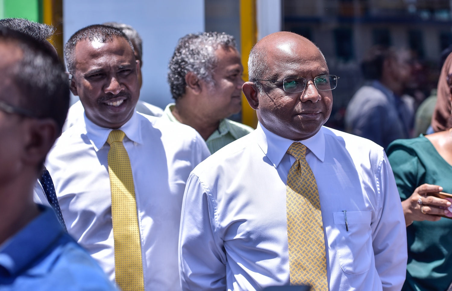 މާލެ: ޖުލައި 23، 2017- ރައްޔިތުންގެ މަޖިލީހުގެ ދިއްގަރު ދާއިރާގެ މެމްބަރު ފާރިސް މައުމޫން ޕީޕީއެމްގެ ދިދަ އާއި ލޯގޯ ގަވާއިދާ ޚިލާފަށް ބޭނުންކުރި ކަމަށް ބުނެ އޭނާގެ މައްޗަށް ކުރާ ދައުވާއާ ގުޅިގެން މިއަދު ކްރިމިނަލް ކޯޓުގައި އަޑުއެހުން ކުރިއަށް ގެންދިޔައިރު، އިދިކޮޅު ބައެއް މެމްބަރުން ކޯޓުން ބޭރުގައި.---މިހާރު ފޮޓޯ: ހުސެއިން ވަހީދު