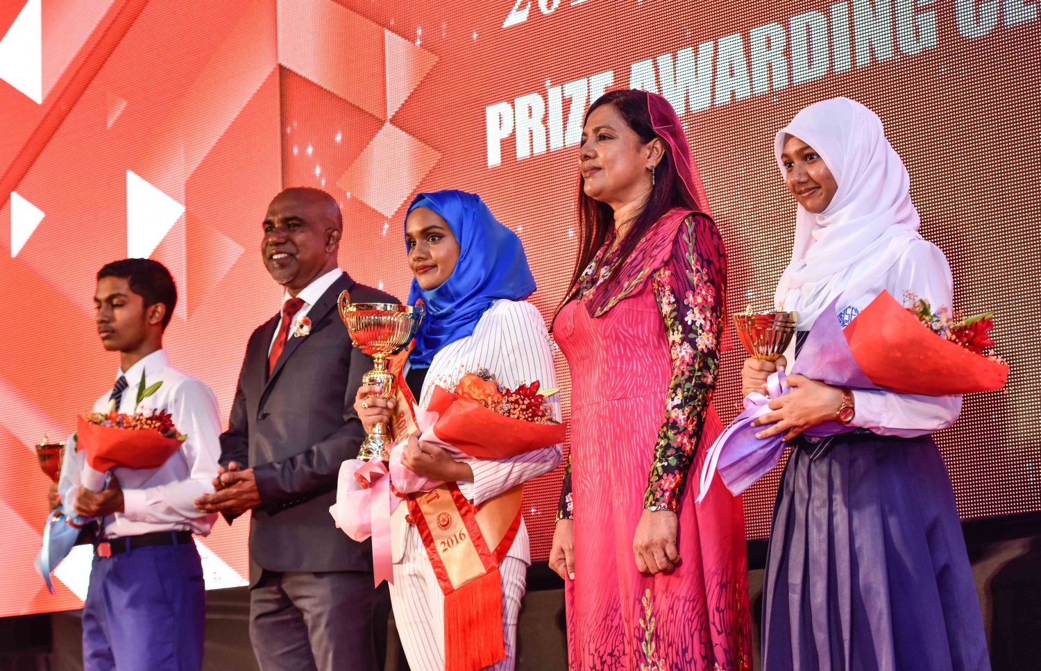 މާލެ: އޮގަސްޓް 10، 2017- އިސްކަންދަރު ސްކޫލުން މިދިޔަ އަހަރު އެއްވަނަ، ދެވަނަ އަދި ތިންވަނަ ހޯދި ދަރިވަރުން، އެޑިއުކޭޝަން މިނިސްޓަރު އައިޝަތު ޝިހާމާއި ސްޓޭޓް މިނިސްޓަރު އަހުމަދު ޝަފީއުއާ އެކު ފޮޓޯއެއް ނަގަނީ.---މިހާރު ފޮޓޯ: ހުސެއިން ވަހީދު