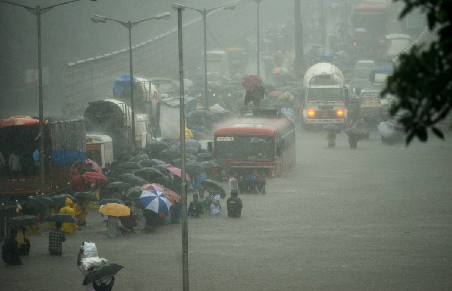 އިންޑިއާގެ މުމްބާއީ އަށް ކުރަމުންދާ ބޯ ވިއްސާރައިގައި ފެންބޮޑުވެފައިވާ މަގަކުން މީހުން ހިނގައިފައި ދަނީ. --ފޮޓޯ:އޭއެފްޕީ