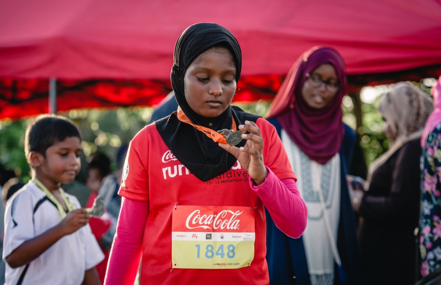 ހިތަދޫ، އައްޑޫ ސިޓީ (ސެޕްޓެމްބަރު 17) – ކޮކާކޯލާ ޓީއެފްޖީ "ރަން އިން އައްޑޫ" އިވެންޓުގައި ބައިވެރިވި ކުއްޖަކު މެޑަލް ބަލާލަނީ. –ފޮޓޯ: އިބްރާހިމް އުޝާފަތު