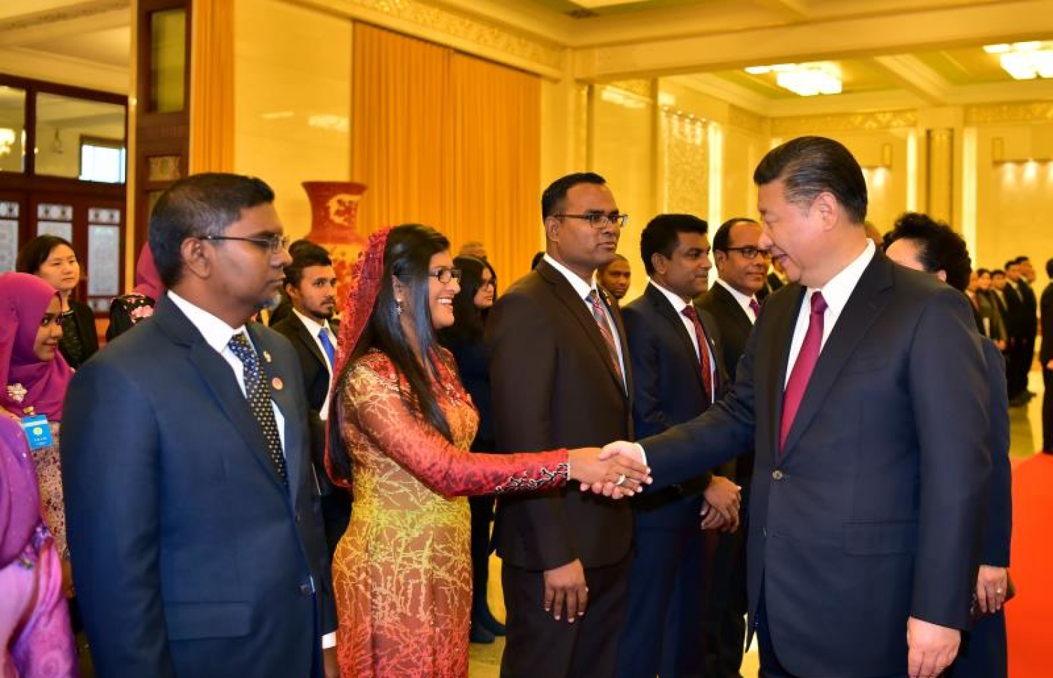 ޗައިނާ، ބެއިޖިން: ޑިސެމްބަރު 7، 2017- ރައީސް އަބްދުﷲ ޔާމީންގެ ދެކަނބަލުންނަށް، ޗައިނާގެ ރައީސްގެ ޝީ ޖިންޕިންގެ ދެކަނބަލުން ރަސްމީކޮށް މަރުހަބާ ދެންނެވުމަށް ބޭއްވި ރަސްމިއްޔާތުގައި، ޗައިނާގައި ހުންނަވާ ދިވެހި ސަފީރު ފައިސަލްގެ އަނބިކަނބަލުން ޖީހާން، ޝީ އާ ސަލާމް ކުރައްވަނީ.---ފޮޓޯ: ރައީސް އޮފީސް