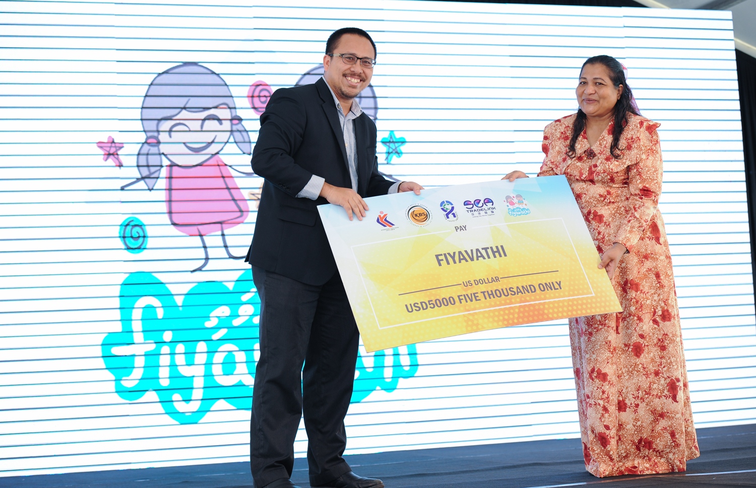 ހުޅުމާލެ: ޑިސެމްބަރު 20، 2017- މެލޭޝިއާގެ ބޮޑުވަޒީރު ނަޖީބު ރައްޒާގުގެ އަނބިކަނބަލުން ޕަޑުކާ ސެރީ ރޮސްމާހް މަންސޫރު، ހުޅުމާލޭގައި ހުންނަ ކުޑަކުދިން ބަލަހައްޓާ މަރުކަޒު ފިޔަވައްޗަށް ކުރެއްވި ޒިޔާރަތުގައި، މެލޭޝިއާގެ އިންޓަނޭޝަނަލް ޔޫތު ސެންޓަރުގެ ފަރާތުން ފިޔަވައްޗަށް ދިން އެހީ ހަވާލުކޮށްދެއްވަނީ.---ފޮޓޯ: ރައީސް އޮފީސް