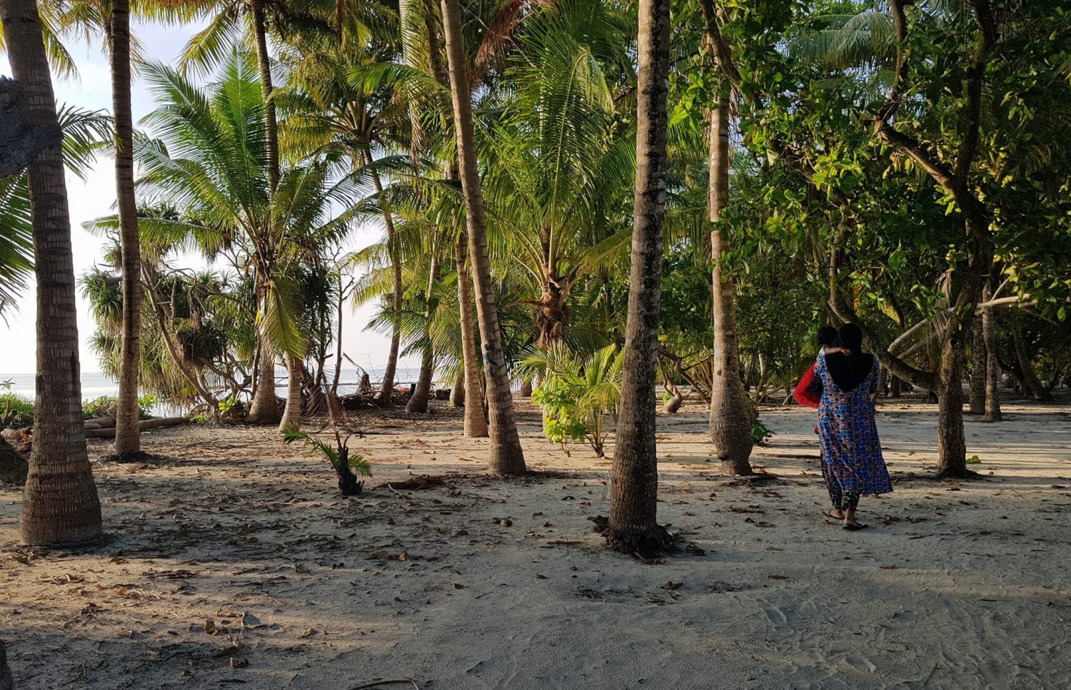 ރަކީދޫ އަންހެނަކު ކުޑަކުއްޖަކު ގޮވައިގެން ރަށުގެ އަތިރިމަތިން ހިނގާފައި ދަނީ. ފޮޓޯ: ނިޔާޝާ އަބްދުއް ލަތީފް