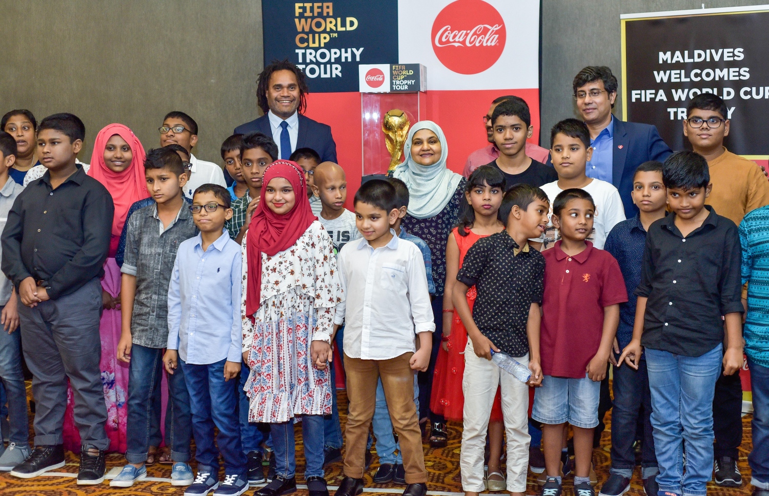 ޖެނުއަރީ 24، 2018- ރަޝިއާގައި ބާއްވާ ފީފާ ވޯލްޑް ކަޕްގެ ކުރިން މުބާރާތުގެ އަސްލު ތަށި ދުނިޔޭގެ ބައެއް ގައުމުތަކަށް ގެންދަން މިހާރު ފަށާފައިވާ "ފީފާ ވޯލްޑްކަޕް ޓްރޮފީ ޓުއާ" ގައި އެ ތަށި ރާއްޖެ ގެނައުމުން ވެލާނާ އިންޓަނޭޝަނަލް އެއާޕޯޓުގައި ބޭއްވި ހަފުލާގައި ފަސްޓް ލޭޑީ ފާތިމަތު އިބްރާހީމް ބައެެއް ކުދިންނާއެކު ފޮޓޯފުޅެއް ނަންގަވަނީ.---ފޮޓޯ: ނިޝާން އަލީ/މިހާރު