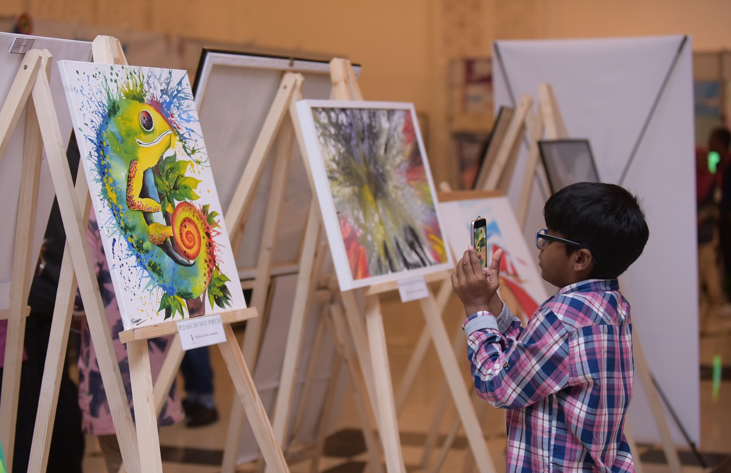 މާލެ: ފެބްރުއަރީ 8، 2018- ޒުވާނުންނަށް ހުރި ވަޒީފާގެ ފުރުސަތުތައް އަންގައި ދިނުމަށް ޔޫތު މިނިސްޓްރީން ކުރިއަށް ގެންދާ މި އަހަރުގެ ޔޫތު ޗެލެންޖުގައި ބަހައްޓާފައި ހުރި ކުރެހުންތަކެއްގެ ފޮޓޯ ކުޑަކުއްޖަކު މޮބައިލް ފޯނުން ނަގަނީ: ދަރުބާރުގޭގައި ބާއްވާ މި ފެއާ ނިމޭނީ ހޮނިހިރު ދުވަހުގެ ރޭ.---ފޮޓޯ: ހުސެއިން ވަހީދު/މިހާރު