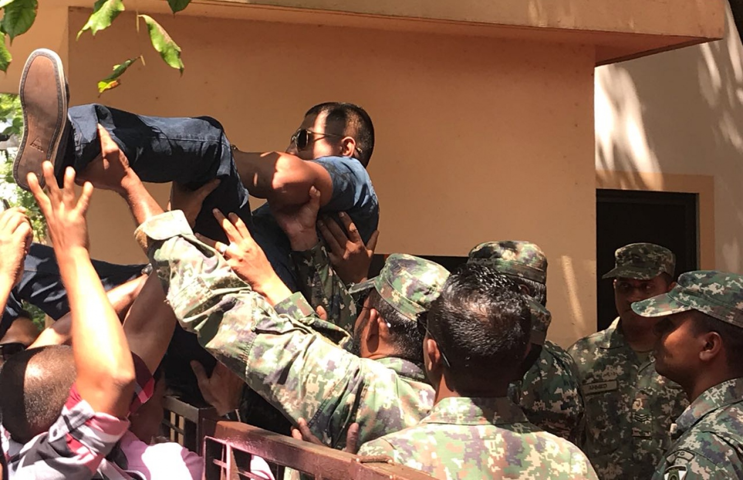 އިދިކޮޅު މެމްބަރުންގެ ތެރޭގައި ހިމެނޭ، ގަލޮޅު ދެކުނު ދާއިރާގެ އަހްމަދު މަހްލޫފް މަޖިލީހަށް ވަދެވަޑައިގަތުމުން ސިފައިން އޭނާ އުފުލާލައިގެން މަޖިލީހުގެ ގޭޓު މަތިން ބޭރުކޮށްލަނީ. --ފޮޓޯ: މިހާރު