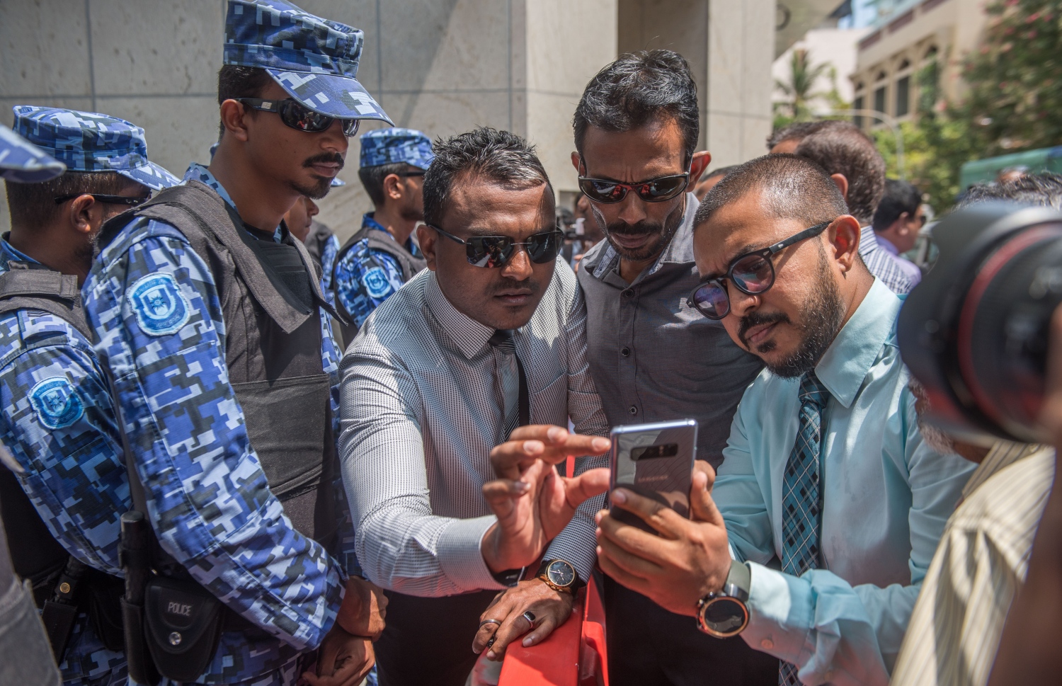 މާލެ: ފެބްރުއަރީ 15، 2018- ރައްޔިތުންގެ މަޖިލީހުގެ އިދާރާ އަށް ވަދެވަޑައިގަންނަވަން އުޅުއްވި އިދިކޮޅު މެމްބަރުންނަށް އެސްއޯ ފުލުހުން ހުރަސްއަޅާފައިވާއިރު، މަޑުއްވަރީ ދާއިރާގެ މެމްބަރު އަމީތު އޭނާގެ ފޯނުން އެހެން މެމްބަރުންނަށް އެއްޗެއް ދައްކާލައްވަނީ.---ފޮޓޯ: ނިޝާން އަލީ/މިހާރު