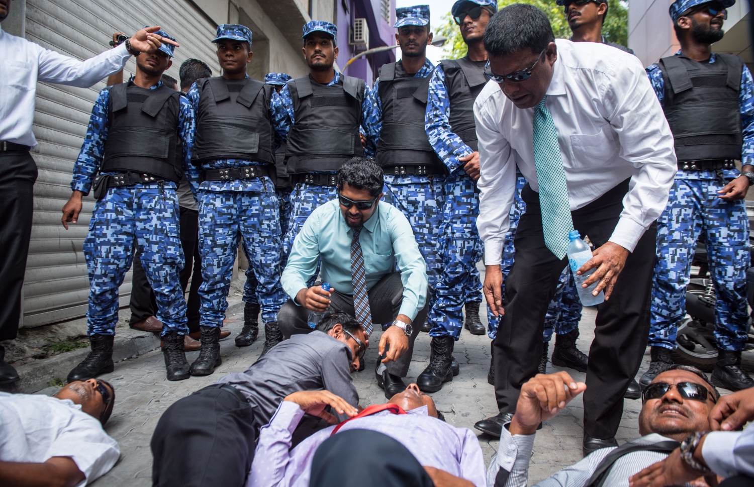 މާލެ: ފެބްރުއަރީ 15، 2018- ރައްޔިތުންގެ މަޖިލީހުގެ އިދިކޮޅު މެމްބަރުން މަޖިލީހުގެ އިދާރާ އަށް ވަދެވަޑައިގަންނަވަން އުޅުއްވުމުން، ފުލުހުންނާ ދެމެދު ހިނގި ހަމަނުޖެހުމުގައި އަނިޔާވި ބައެއް މެމްބަރުން މަޖިލީހުގެ އިދާރާގެ ކައިރީގެ ބިންމަތީގައި.---ފޮޓޯ: ނިޝާން އަލީ/މިހާރު