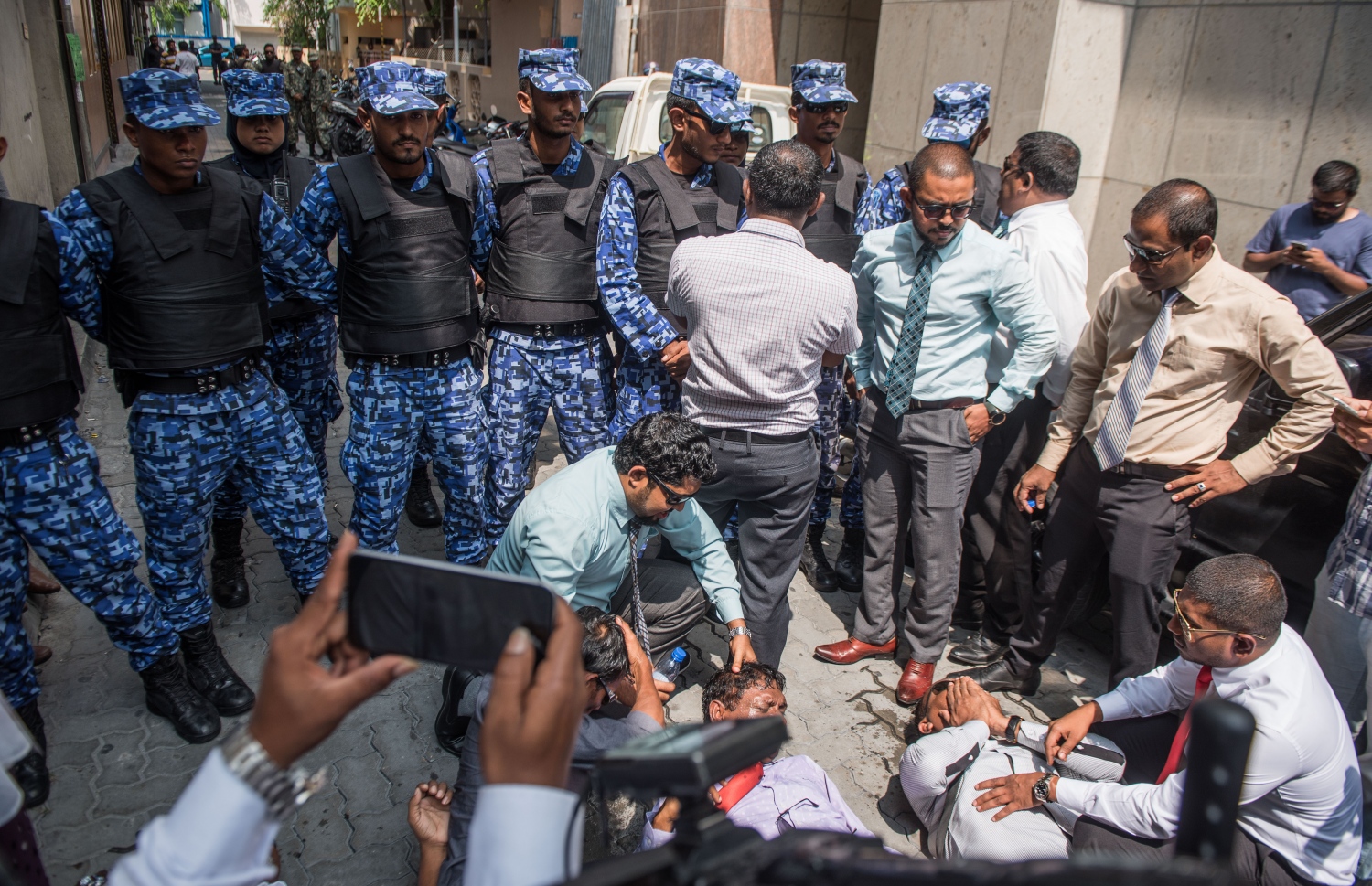 މާލެ: ފެބްރުއަރީ 15، 2018- ރައްޔިތުންގެ މަޖިލީހުގެ އިދިކޮޅު މެމްބަރުން މަޖިލީހުގެ އިދާރާ އަށް ވަދެވަޑައިގަންނަވަން އުޅުއްވުމުން، ފުލުހުންނާ ދެމެދު ހިނގި ހަމަނުޖެހުމުގައި އަނިޔާވި ބައެއް މެމްބަރުން މަޖިލީހުގެ އިދާރާގެ ކައިރީގެ ބިންމަތީގައި.---ފޮޓޯ: ނިޝާން އަލީ/މިހާރު